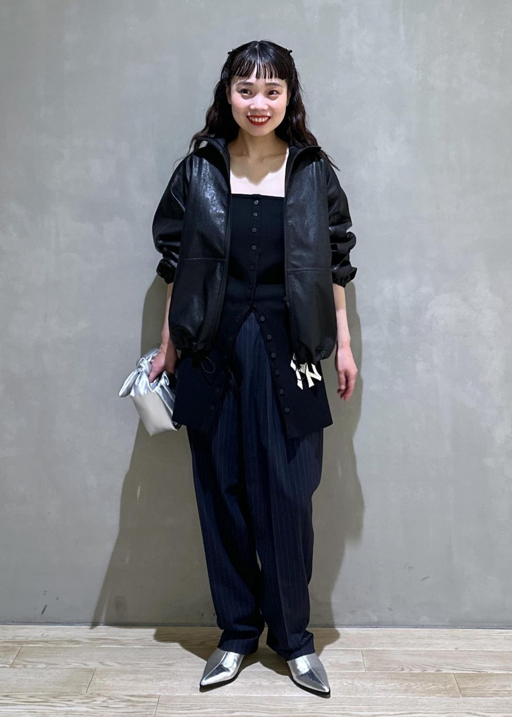 シルバー系のショルダーバッグ、シルバー系のブーツ、ブラック系のスラックスを着用したレディースの秋コーディネートの2枚目の写真