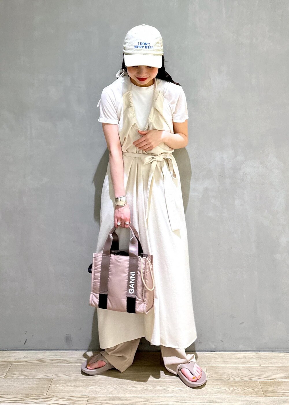 グレー系のショルダーバッグ、ベージュ系のスラックスを着用したレディースの夏コーディネートの3枚目の写真