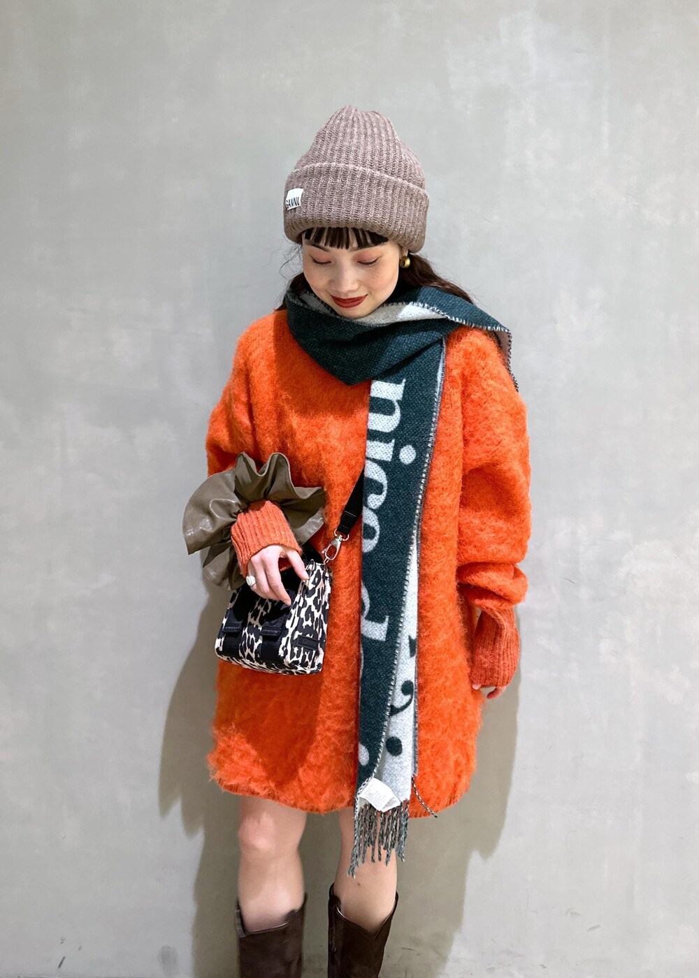 ベージュ系のトートバッグ、オレンジ系のワンピース、ブラウン系のシュシュを着用したレディースの秋コーディネートの7枚目の写真