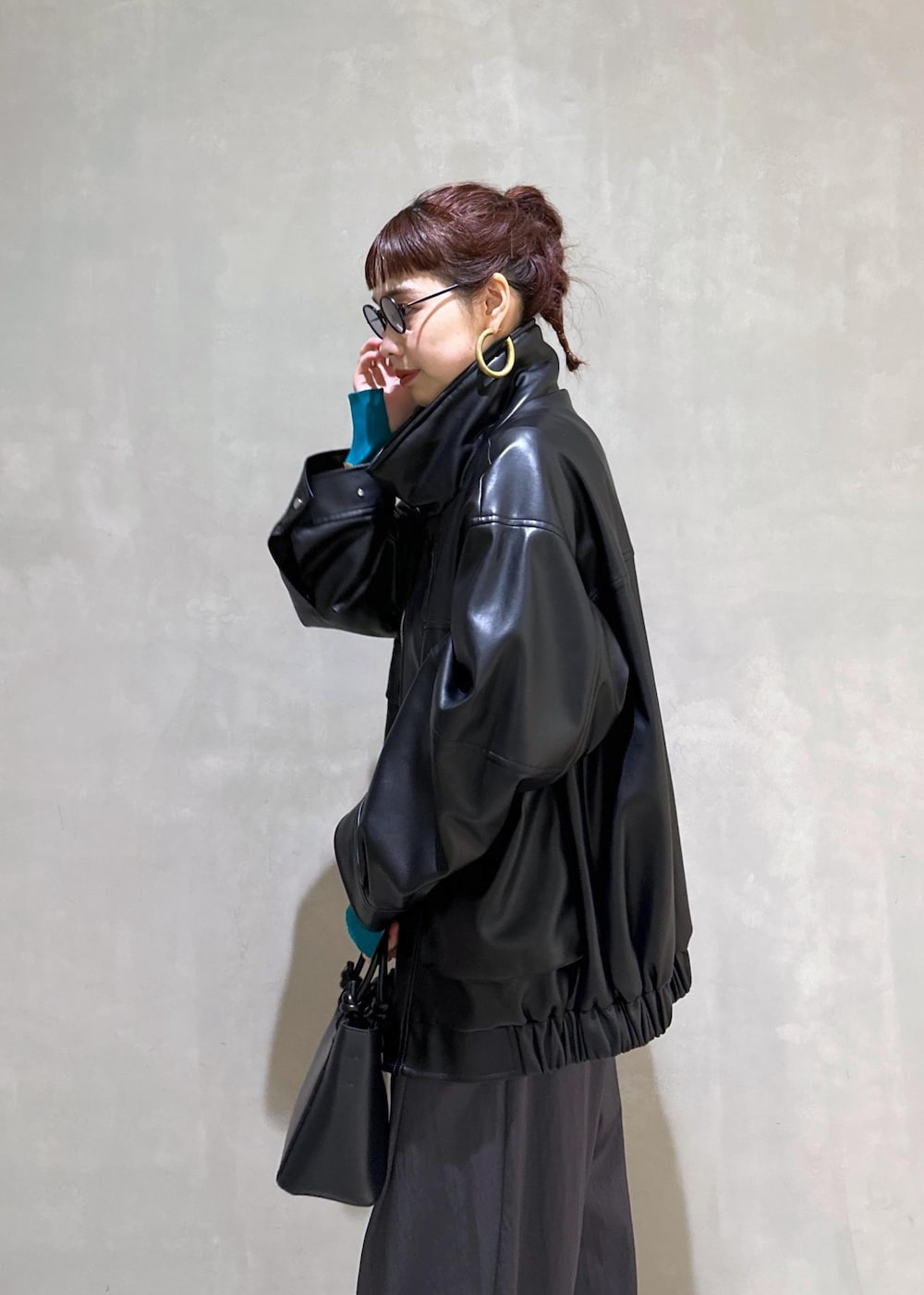 ブラック系のハンドバッグ、ブラック系のライダースジャケット、ブルー系のニット/セーターを着用したレディースの秋コーディネートの6枚目の写真