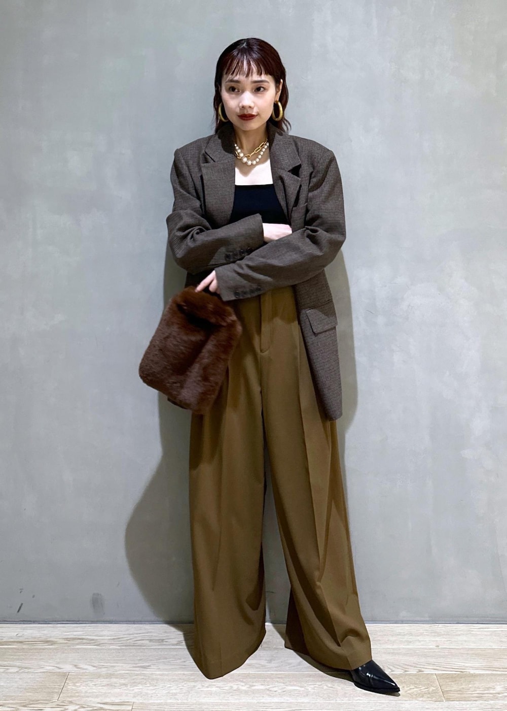 ブラウン系のスラックス、ブラック系のパンプス、ブラウン系のトートバッグを着用したレディースの秋コーディネートの2枚目の写真