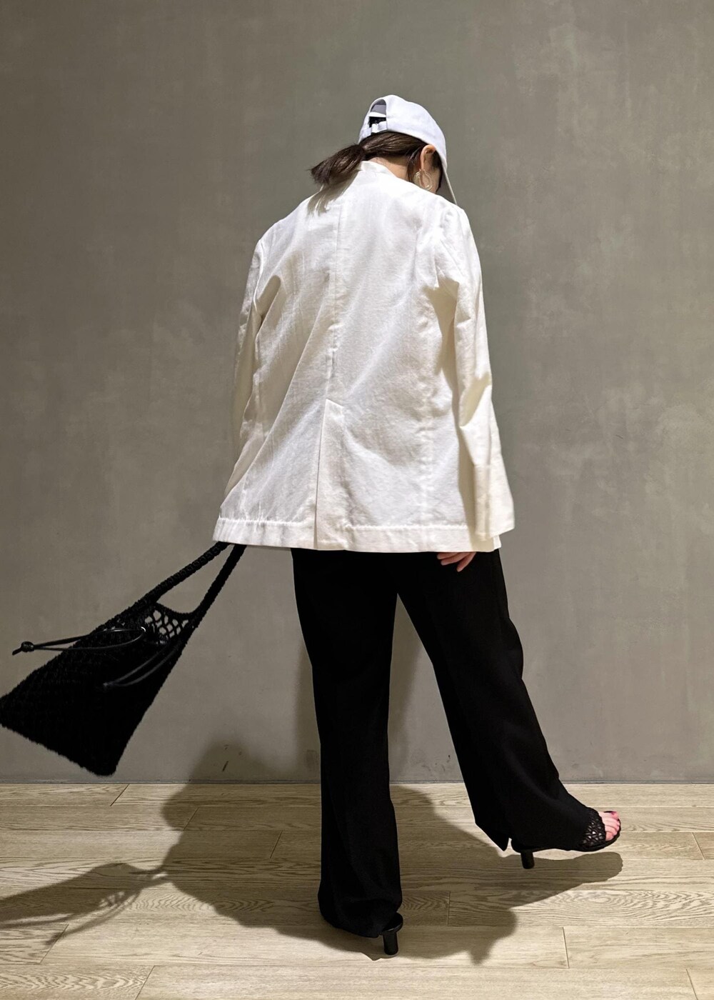 ホワイト系のタンクトップ、ホワイト系のテーラードジャケット、ブラック系のハンドバッグを着用したレディースの夏コーディネートの3枚目の写真