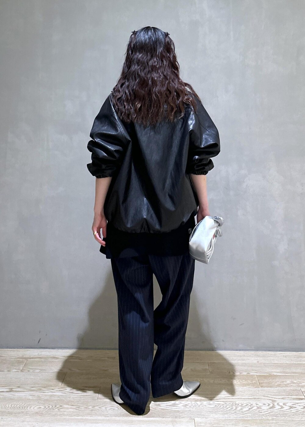 シルバー系のショルダーバッグ、シルバー系のブーツ、ブラック系のスラックスを着用したレディースの秋コーディネートの5枚目の写真