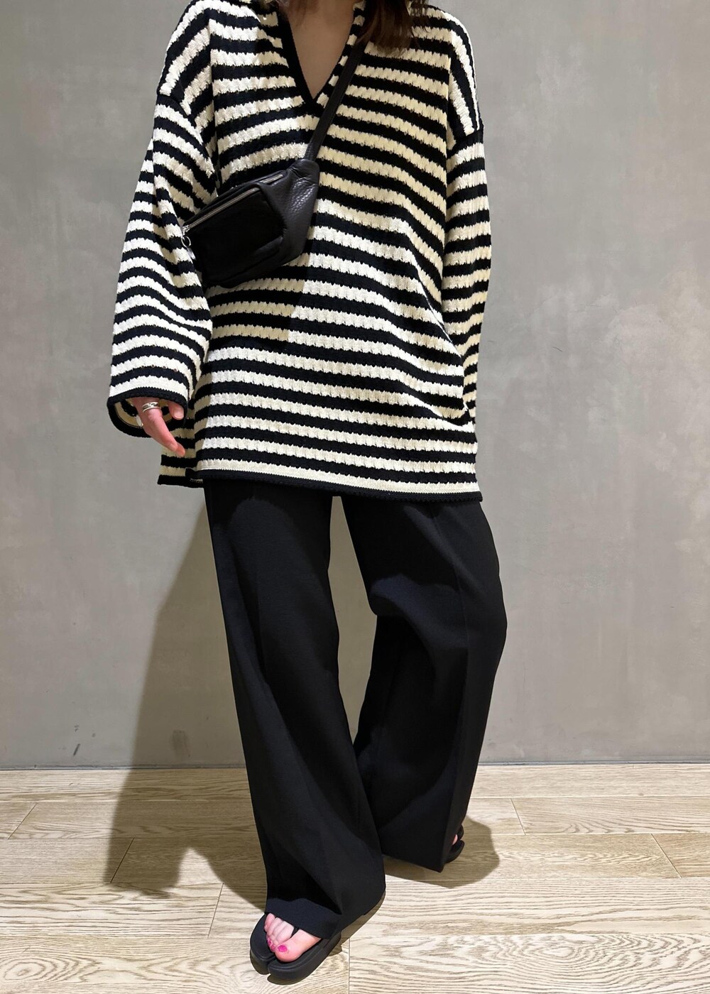 ブラック系のニット/セーター、ブラック系のスラックス、ブラック系のサンダルを着用したレディースの夏コーディネートの8枚目の写真