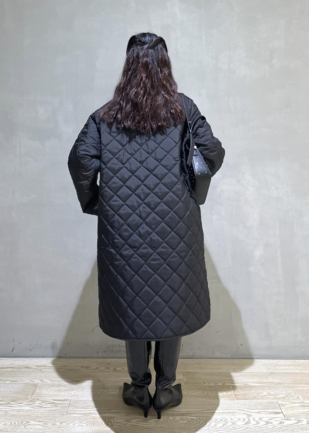 ブラック系のニット/セーター、ブラック系のナイロンジャケット、ブラック系のブーツを着用したレディースの秋コーディネートの3枚目の写真