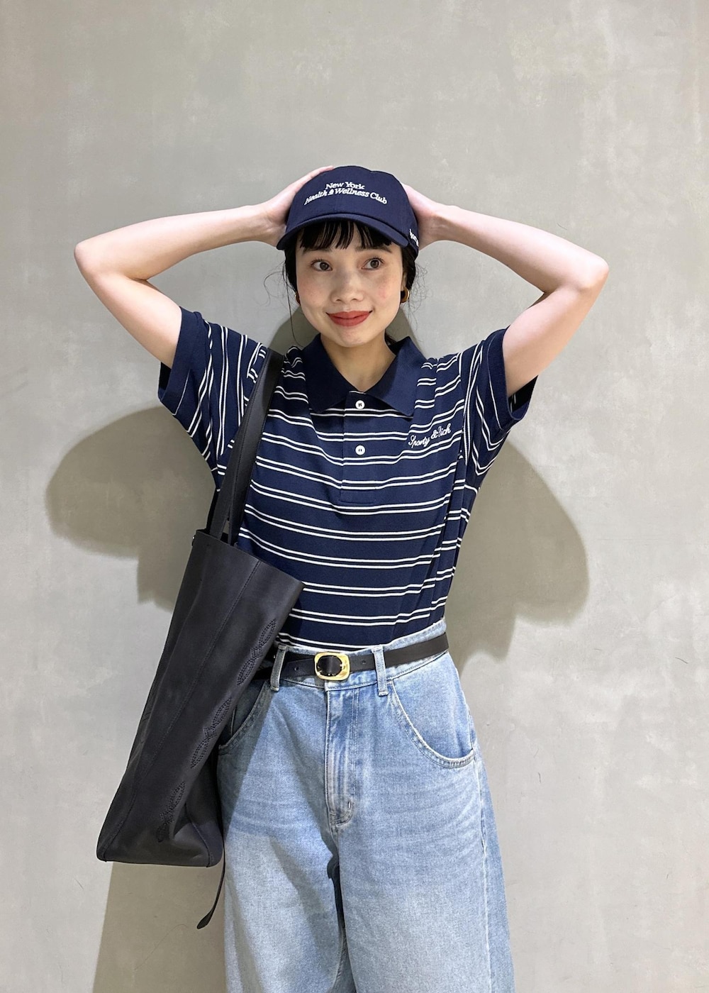 ブルー系のデニムパンツ、ブルー系のポロシャツ、ゴールド系のベルトを着用したレディースの夏コーディネートの5枚目の写真