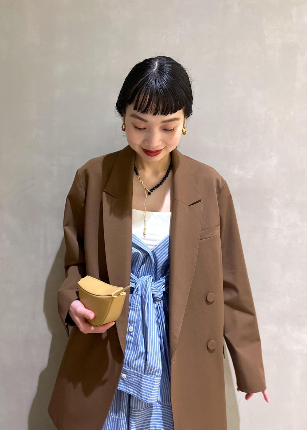 ブラック系のサンダル、ブラウン系のテーラードジャケット、ブルー系のシャツワンピースを着用したレディースの秋コーディネートの8枚目の写真