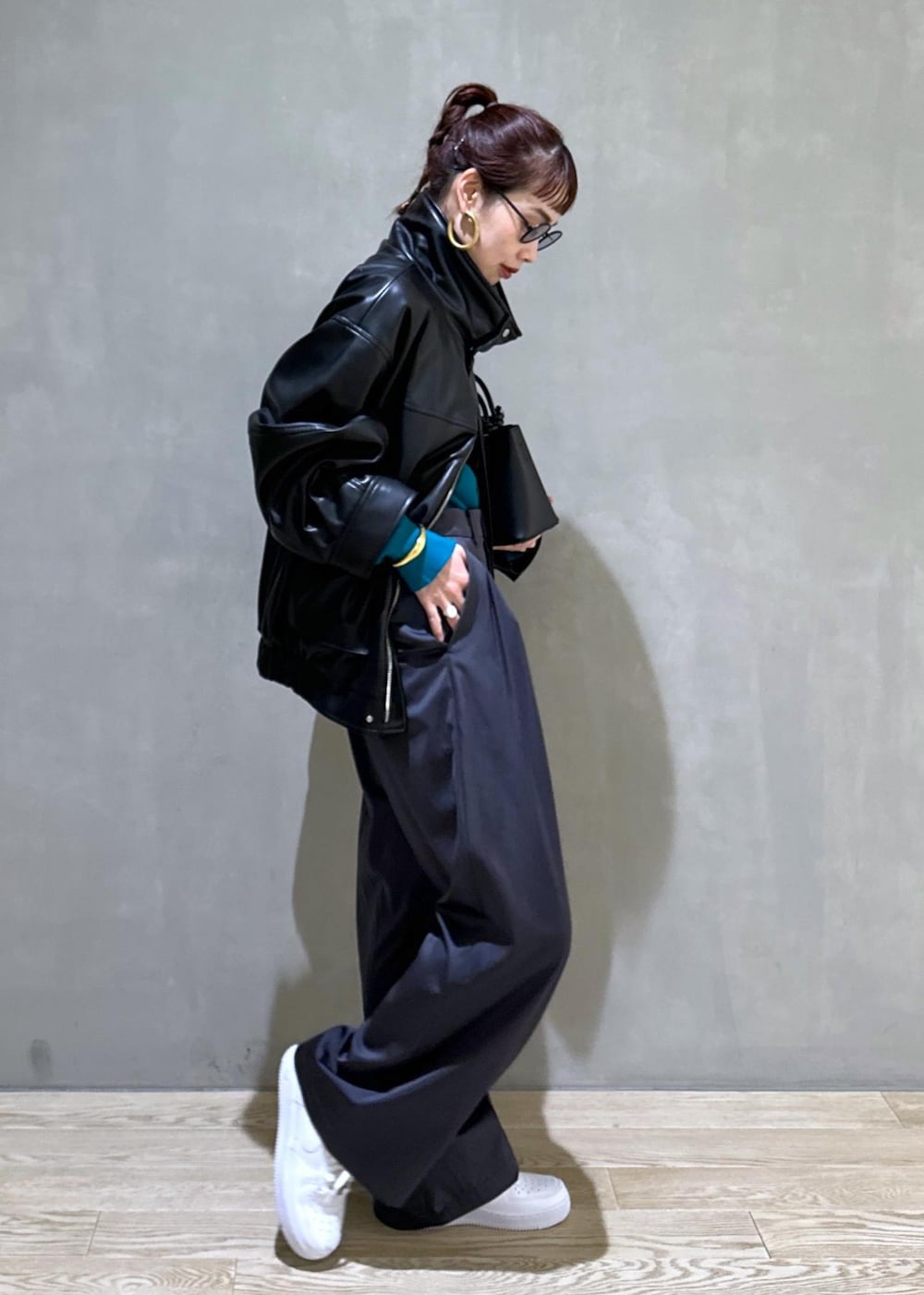 ブラック系のハンドバッグ、ブラック系のライダースジャケット、ブルー系のニット/セーターを着用したレディースの秋コーディネートの4枚目の写真