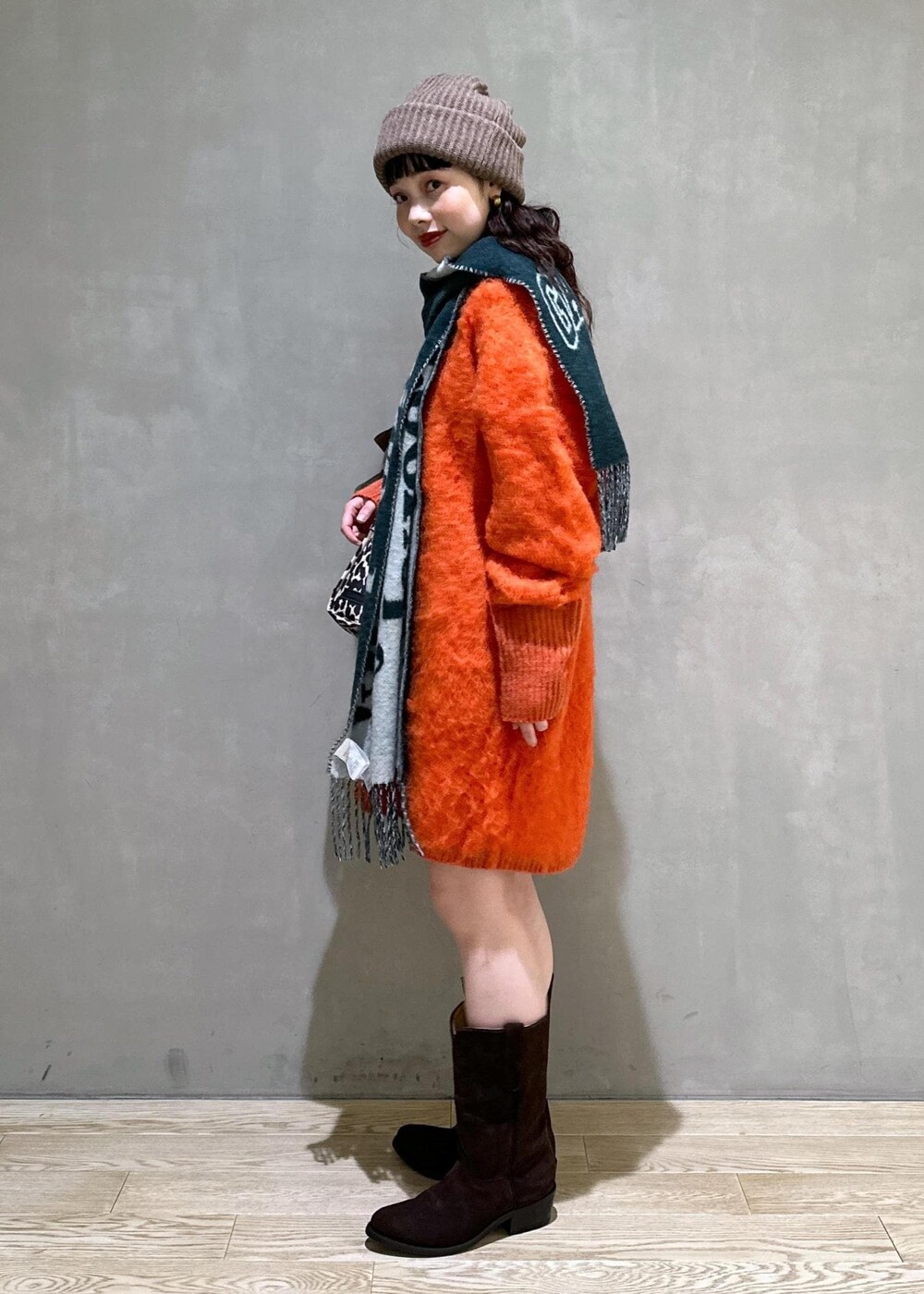 ベージュ系のトートバッグ、オレンジ系のワンピース、ブラウン系のシュシュを着用したレディースの秋コーディネートの3枚目の写真