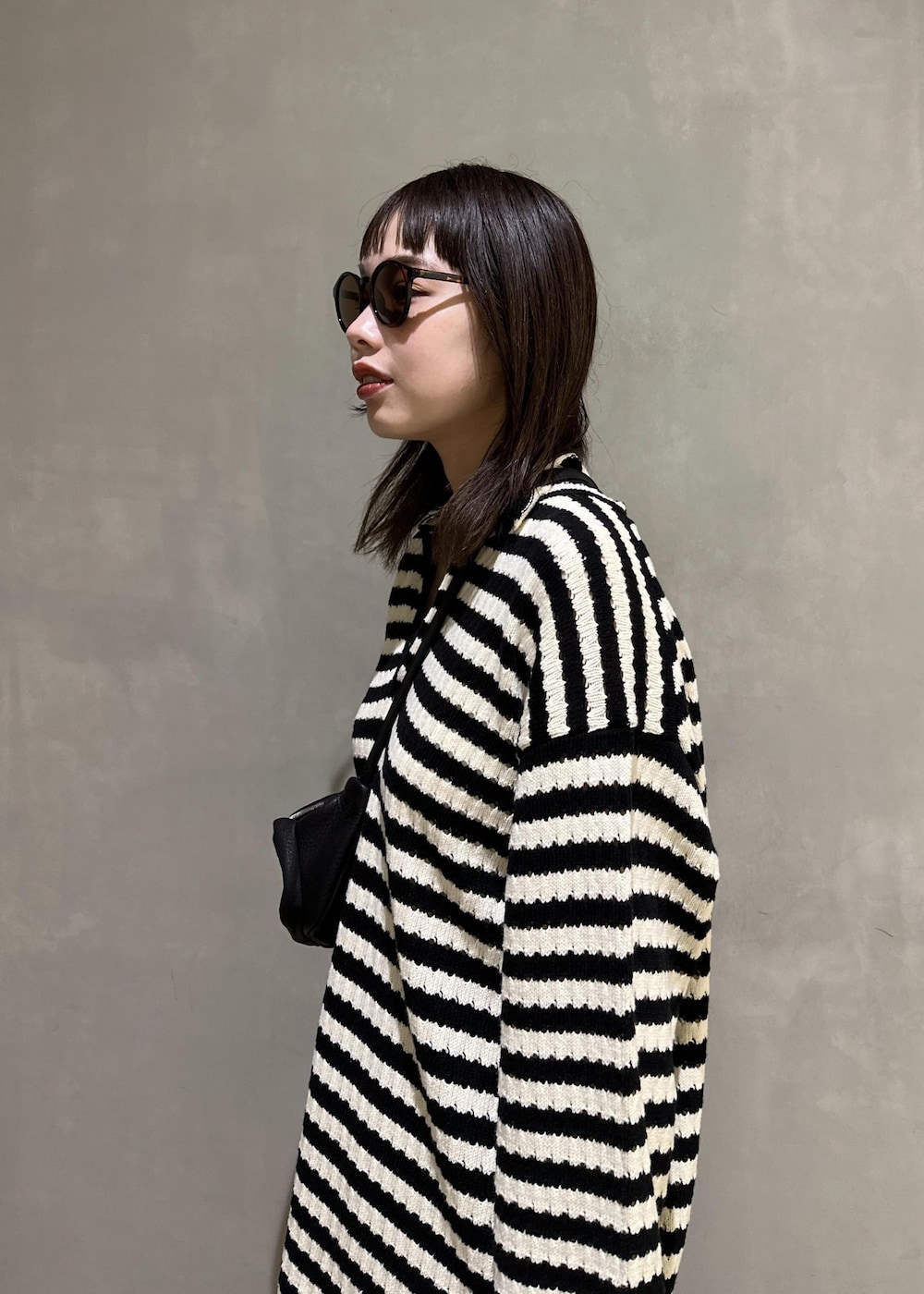 ブラック系のニット/セーター、ブラック系のスラックス、ブラック系のサンダルを着用したレディースの夏コーディネートの7枚目の写真