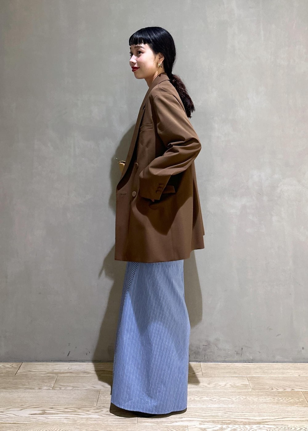 ブラック系のサンダル、ブラウン系のテーラードジャケット、ブルー系のシャツワンピースを着用したレディースの秋コーディネートの3枚目の写真