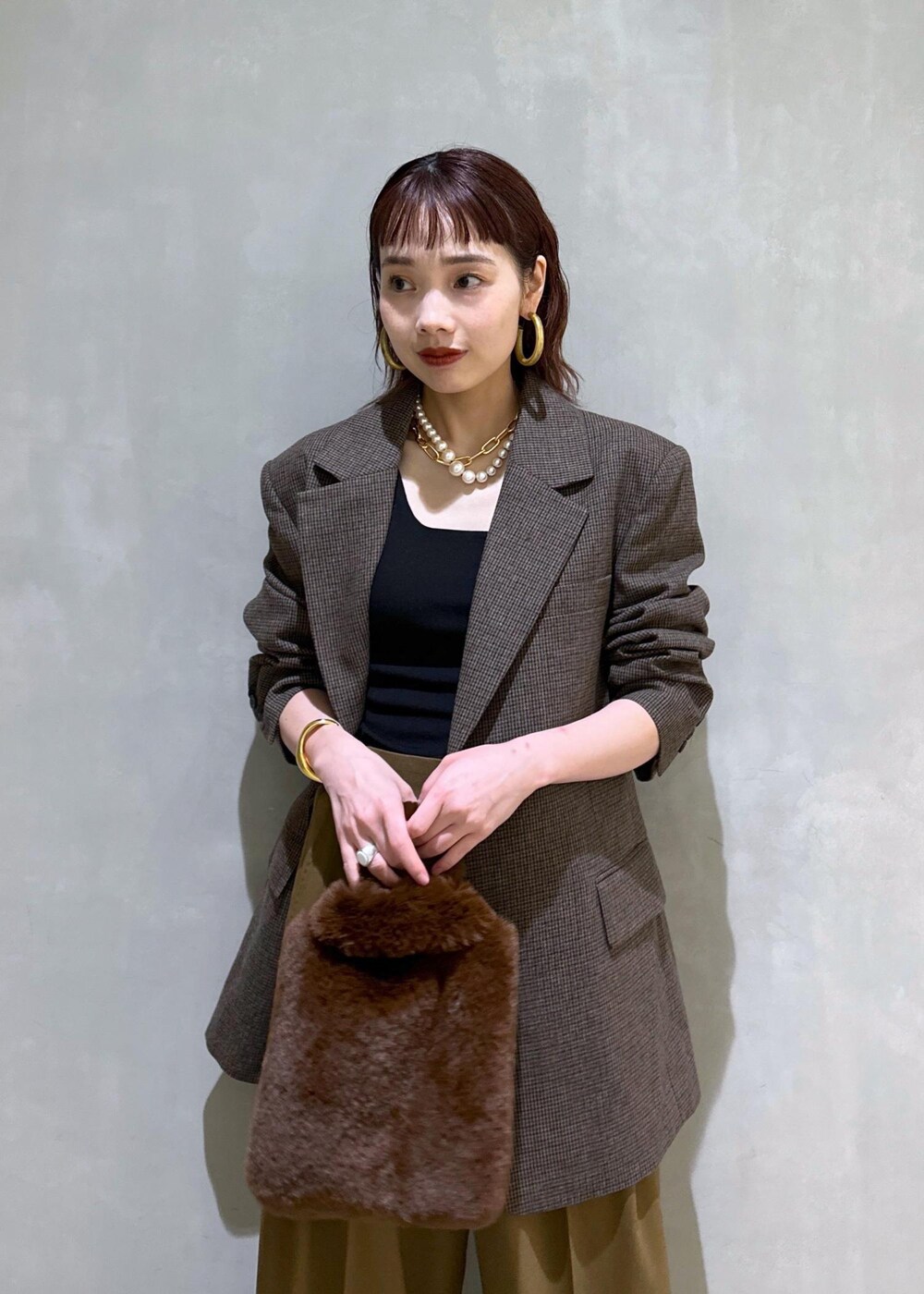 ブラウン系のスラックス、ブラック系のパンプス、ブラウン系のトートバッグを着用したレディースの秋コーディネートの5枚目の写真