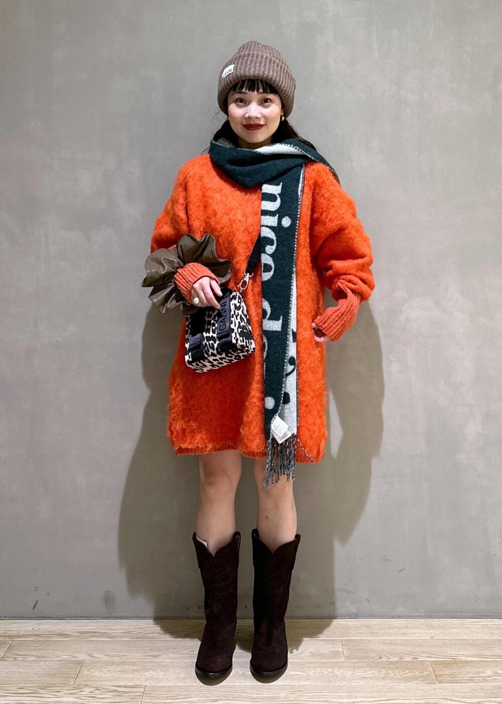 ベージュ系のトートバッグ、オレンジ系のワンピース、ブラウン系のシュシュを着用したレディースの秋コーディネートの2枚目の写真