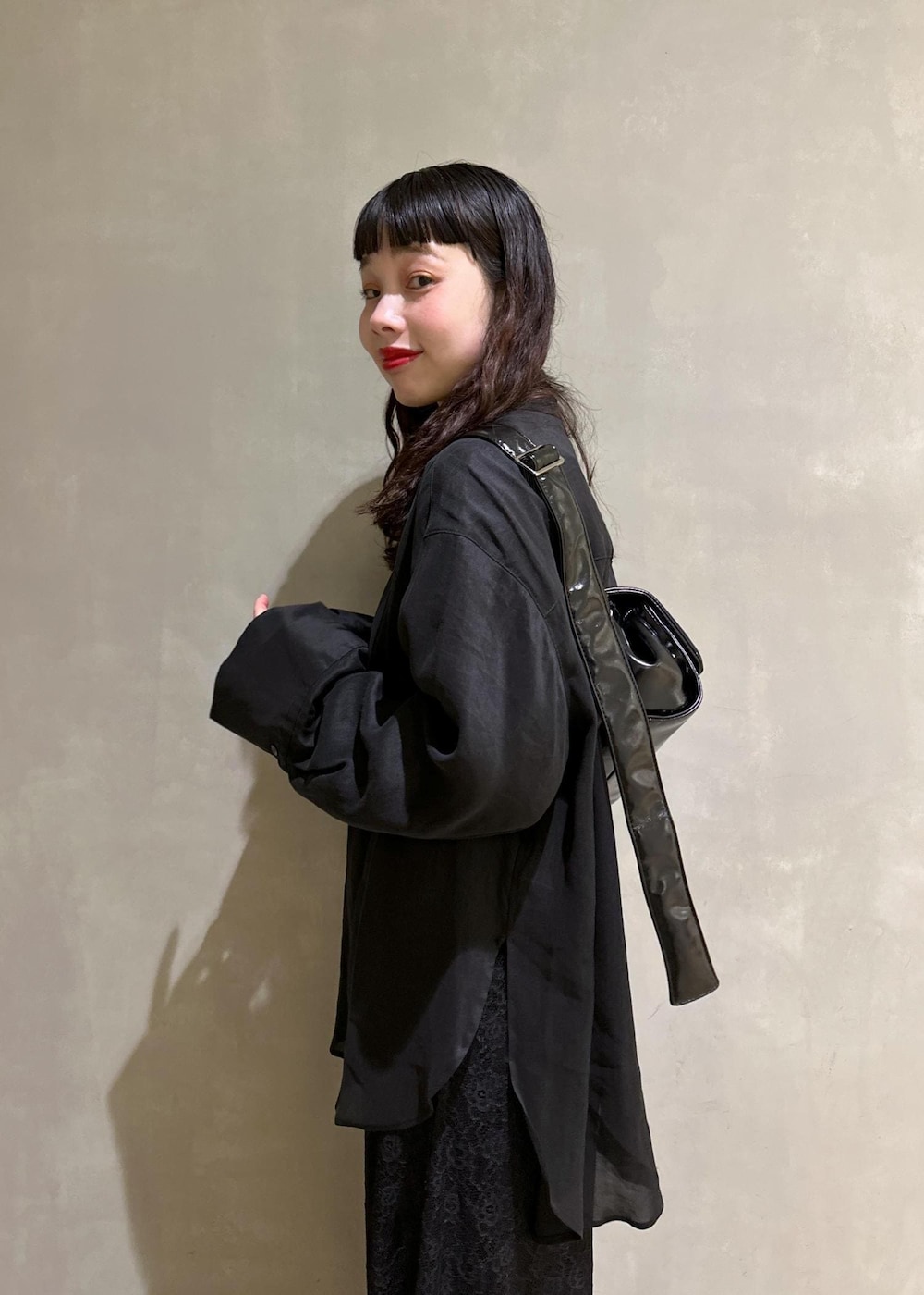 ブラック系のシャツ/ブラウス、ブラック系のショルダーバッグ、グリーン系のサンダルを着用したレディースの春コーディネートの6枚目の写真