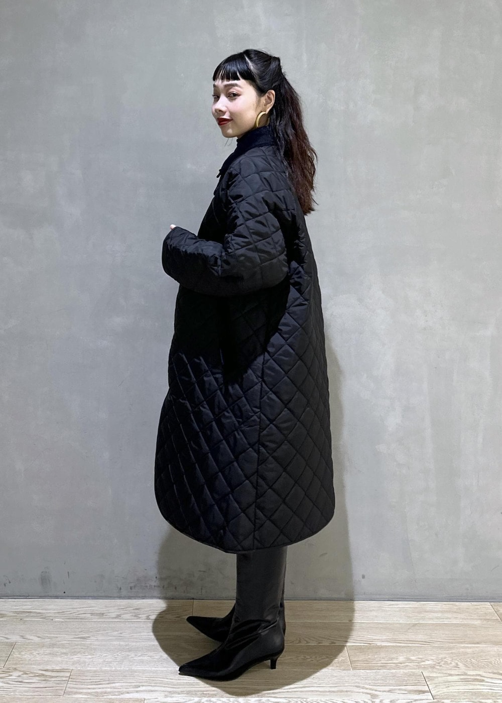 ブラック系のニット/セーター、ブラック系のナイロンジャケット、ブラック系のブーツを着用したレディースの秋コーディネートの2枚目の写真