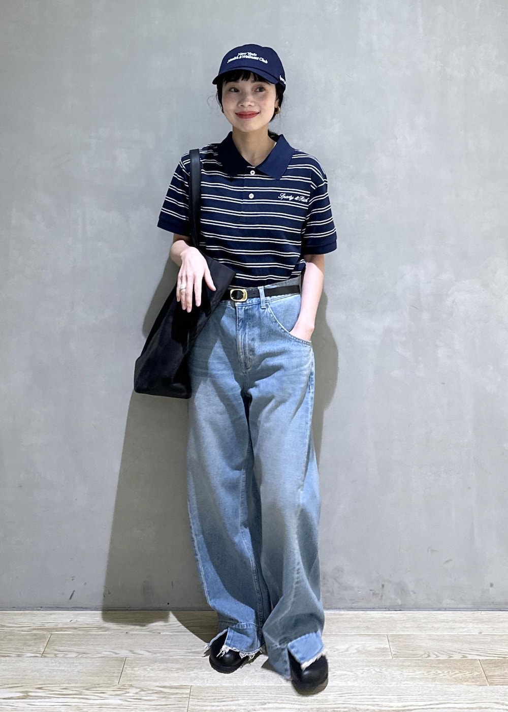 ブルー系のデニムパンツ、ブルー系のポロシャツ、ゴールド系のベルトを着用したレディースの夏コーディネートの3枚目の写真