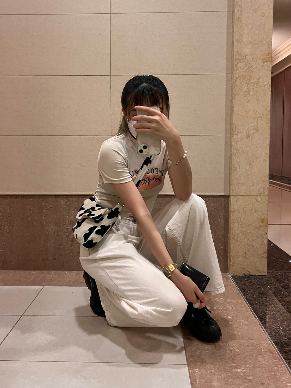 ベージュ系のTシャツ/カットソー、ホワイト系のスラックス、ブラック系のスニーカーを着用したレディースの春コーディネートの2枚目の写真