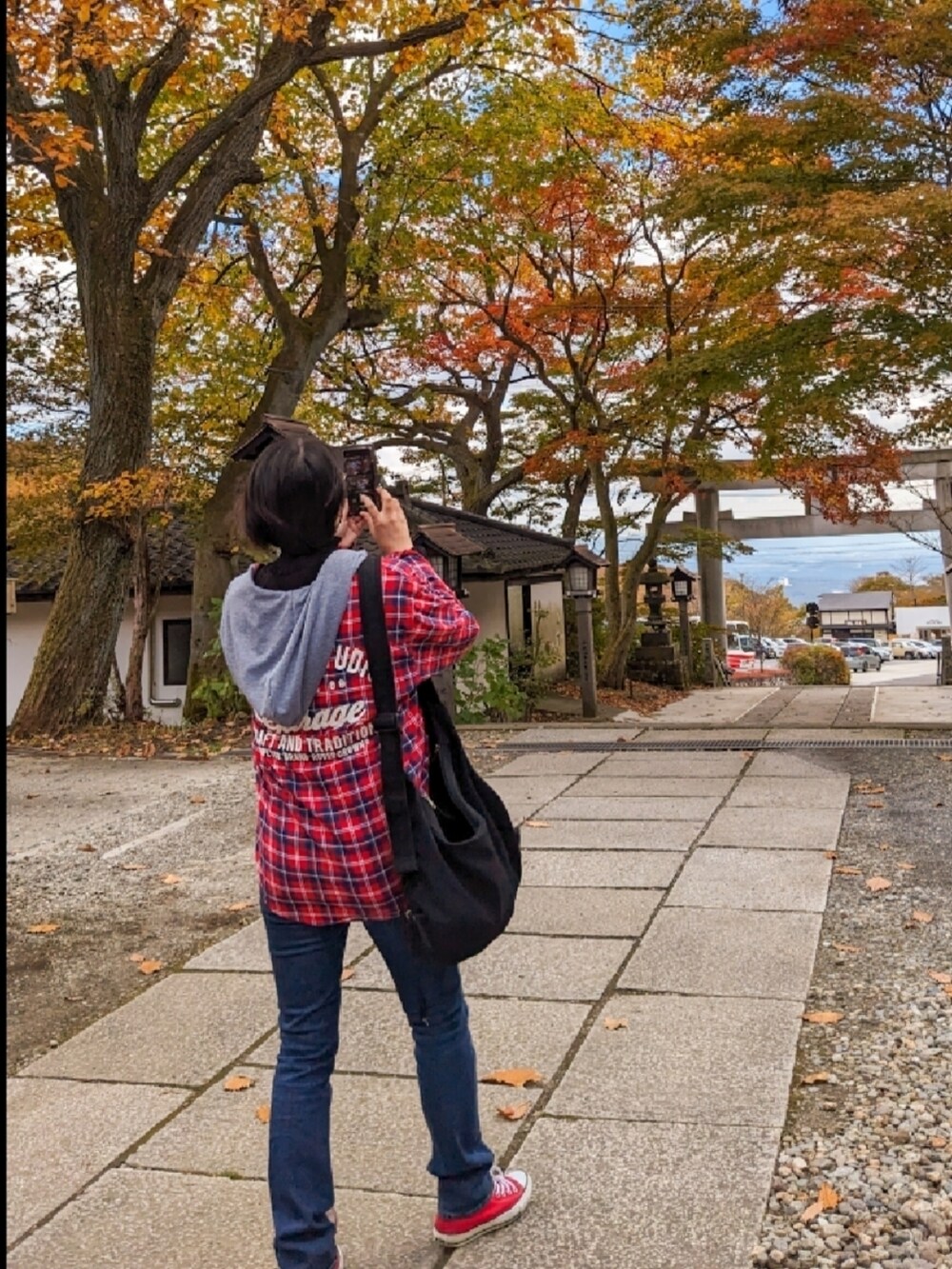 レッド系のシャツ/ブラウス、ブルー系のデニムパンツ、レッド系のスニーカーを着用したレディースの秋コーディネートの4枚目の写真