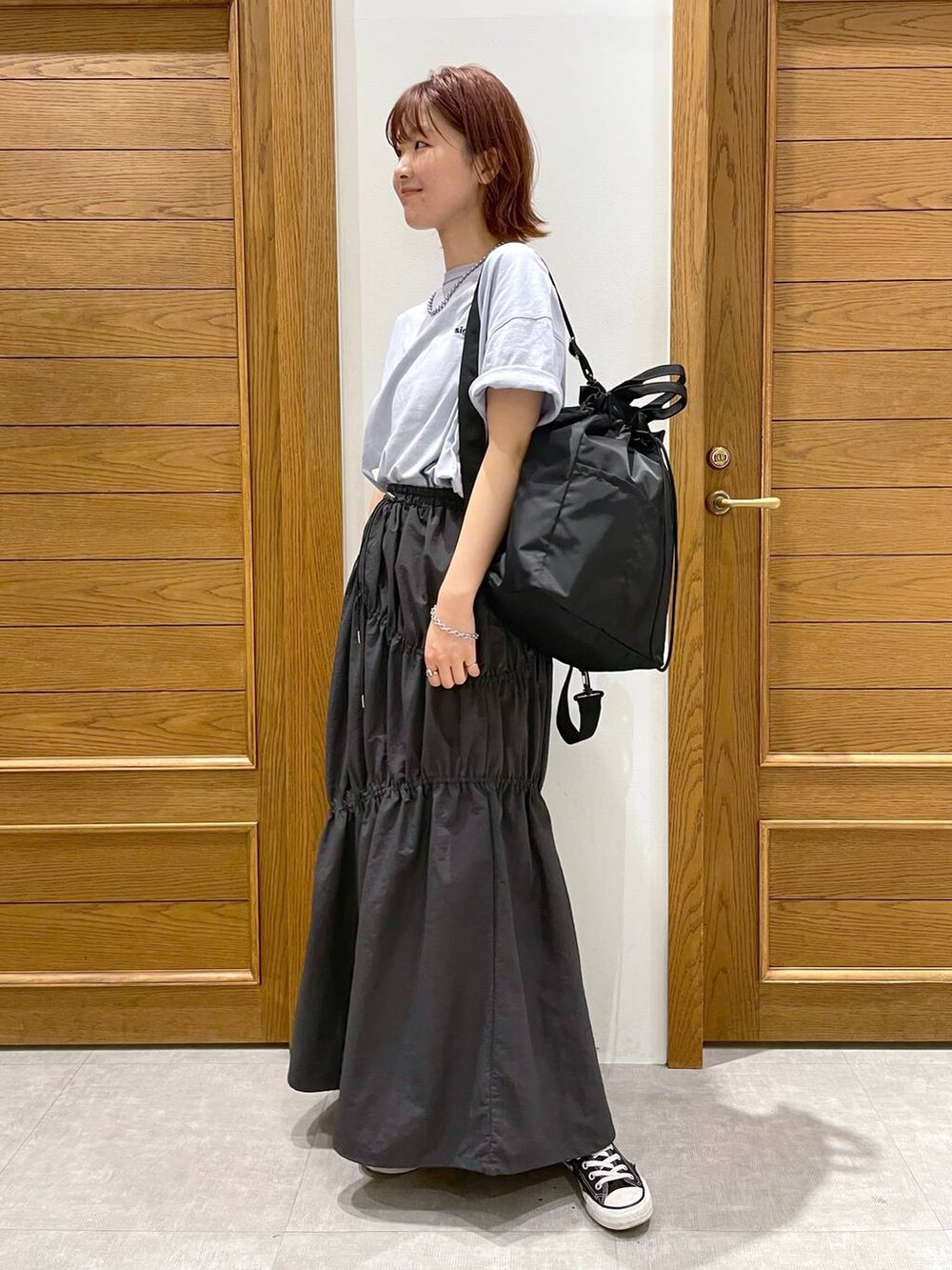 ブラック系のショルダーバッグ、ブルー系のTシャツ/カットソー、グレー系のスカートを着用したレディースの夏コーディネートの5枚目の写真