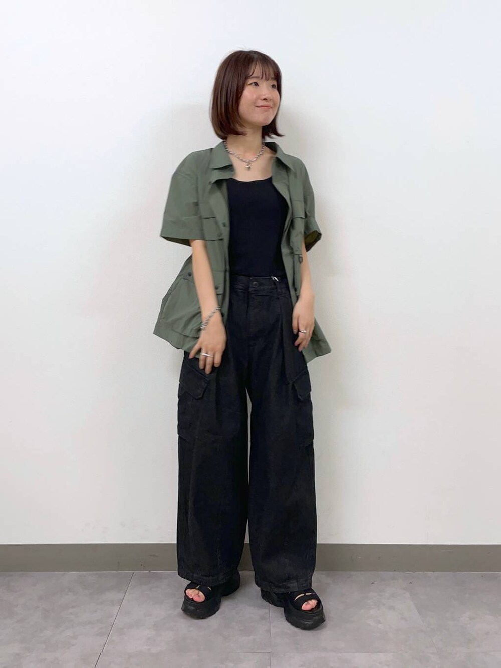 グレー系のデニムパンツ、グリーン系のシャツ/ブラウス、ブラック系のサンダルを着用したレディースの夏コーディネートの4枚目の写真