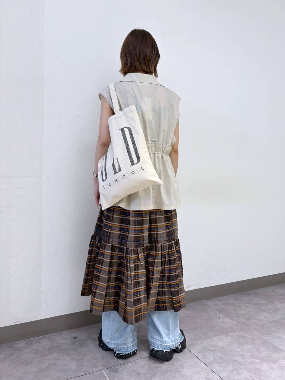 ブラック系のサンダル、ブルー系のデニムパンツ、ホワイト系のベストを着用したレディースの夏コーディネートの3枚目の写真