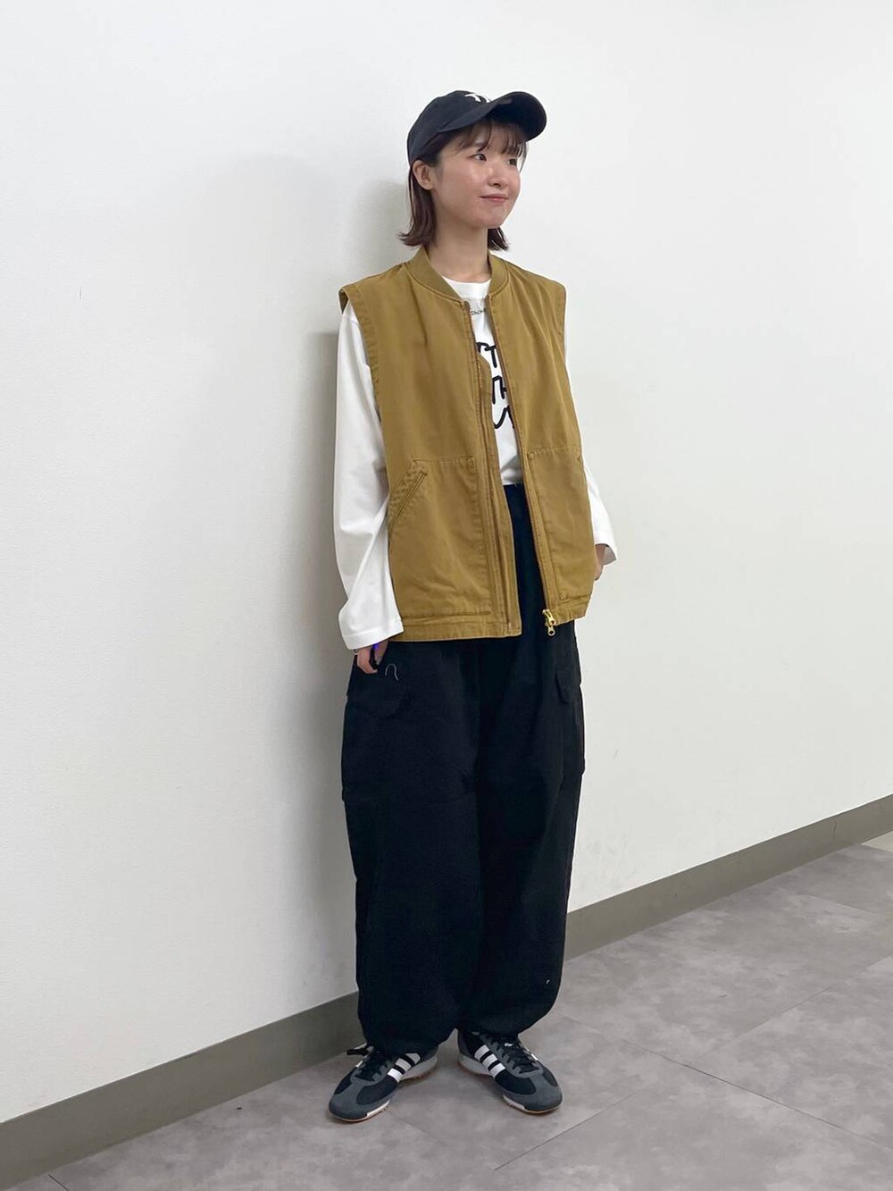 ブラック系のカーゴパンツ、ブラウン系のベスト、ホワイト系のTシャツ/カットソーを着用したレディースの秋コーディネートの5枚目の写真