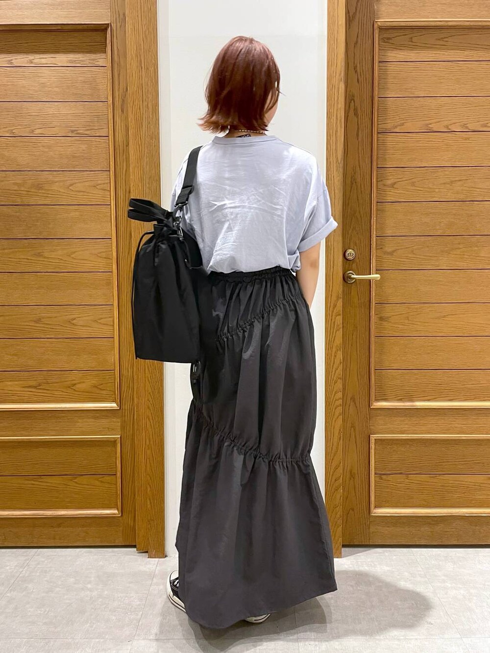 ブラック系のショルダーバッグ、ブルー系のTシャツ/カットソー、グレー系のスカートを着用したレディースの夏コーディネートの4枚目の写真