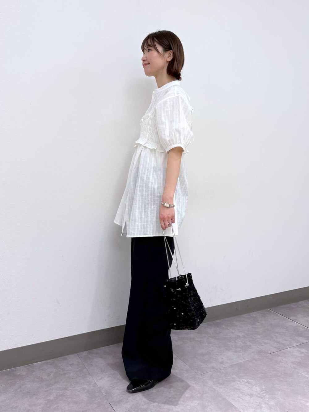 ブラック系のスラックス、ホワイト系のシャツ/ブラウス、ブラック系のハンドバッグを着用したレディースの春コーディネートの3枚目の写真