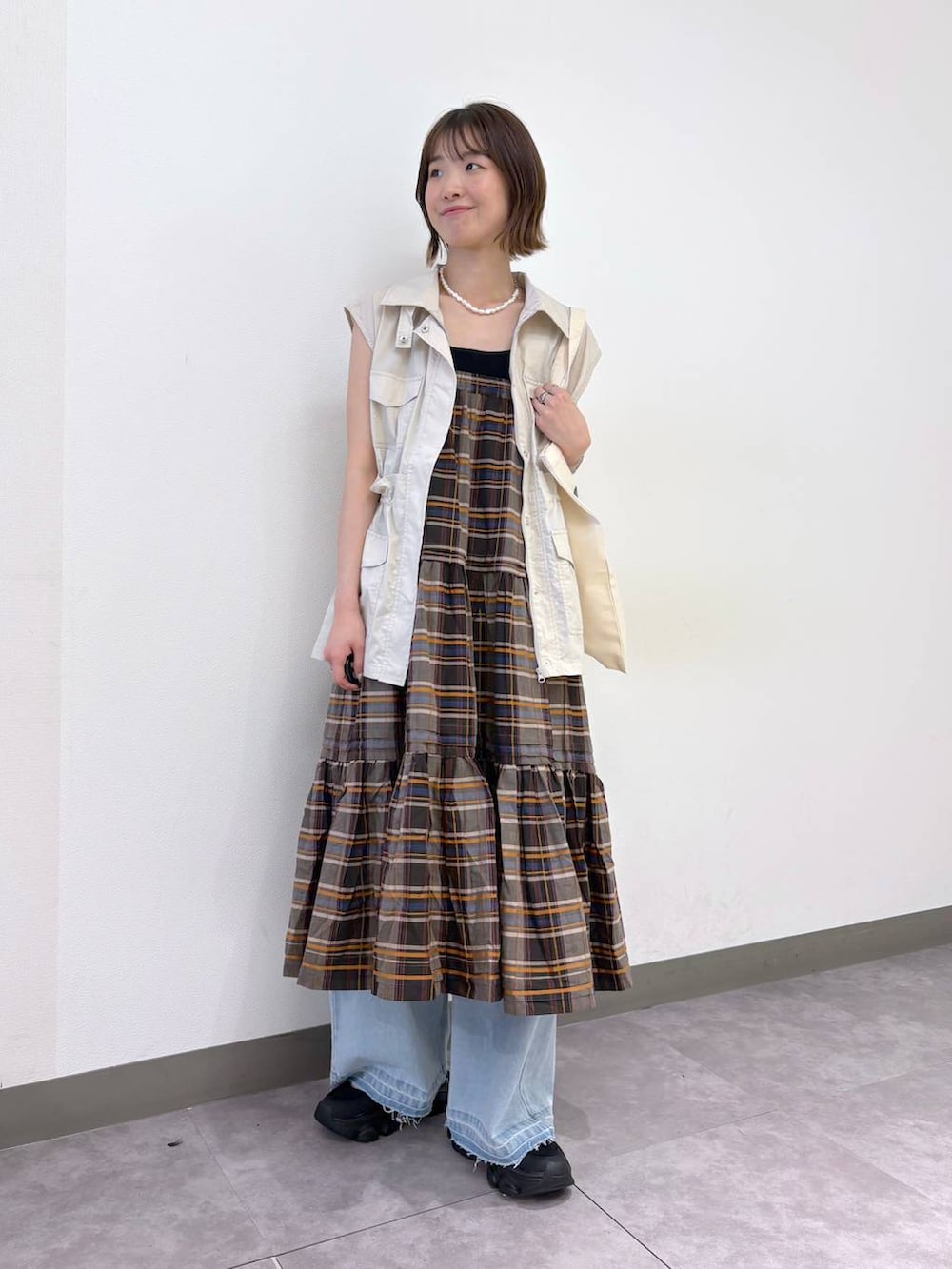 ブラック系のサンダル、ブルー系のデニムパンツ、ホワイト系のベストを着用したレディースの夏コーディネートの5枚目の写真