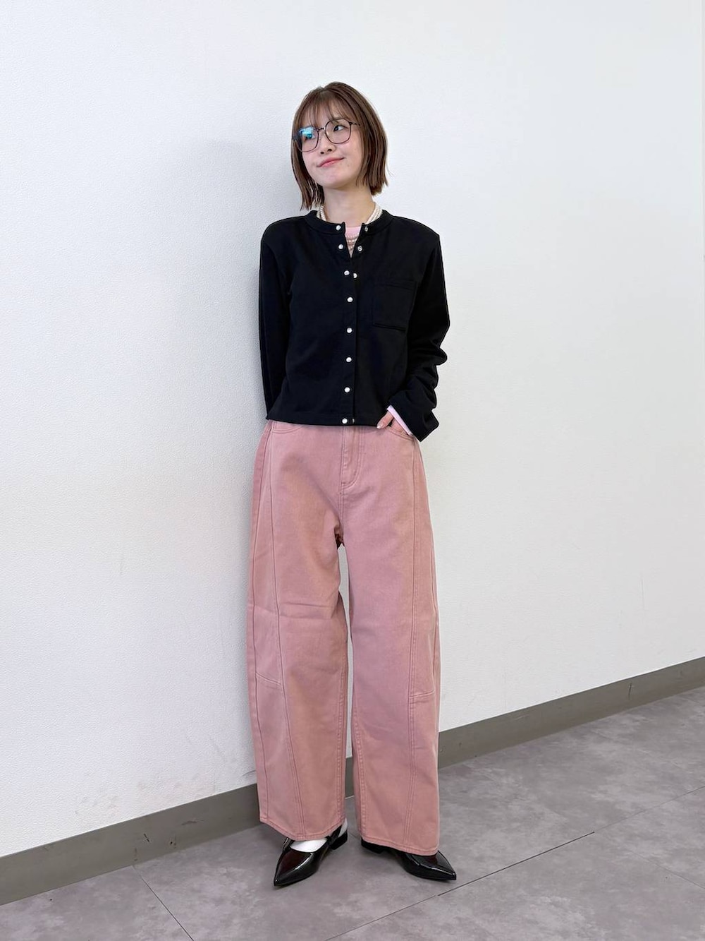 ブラック系のパンプス、ブラック系のカーディガン/ボレロ、ピンク系のデニムパンツを着用したレディースの冬コーディネートの2枚目の写真