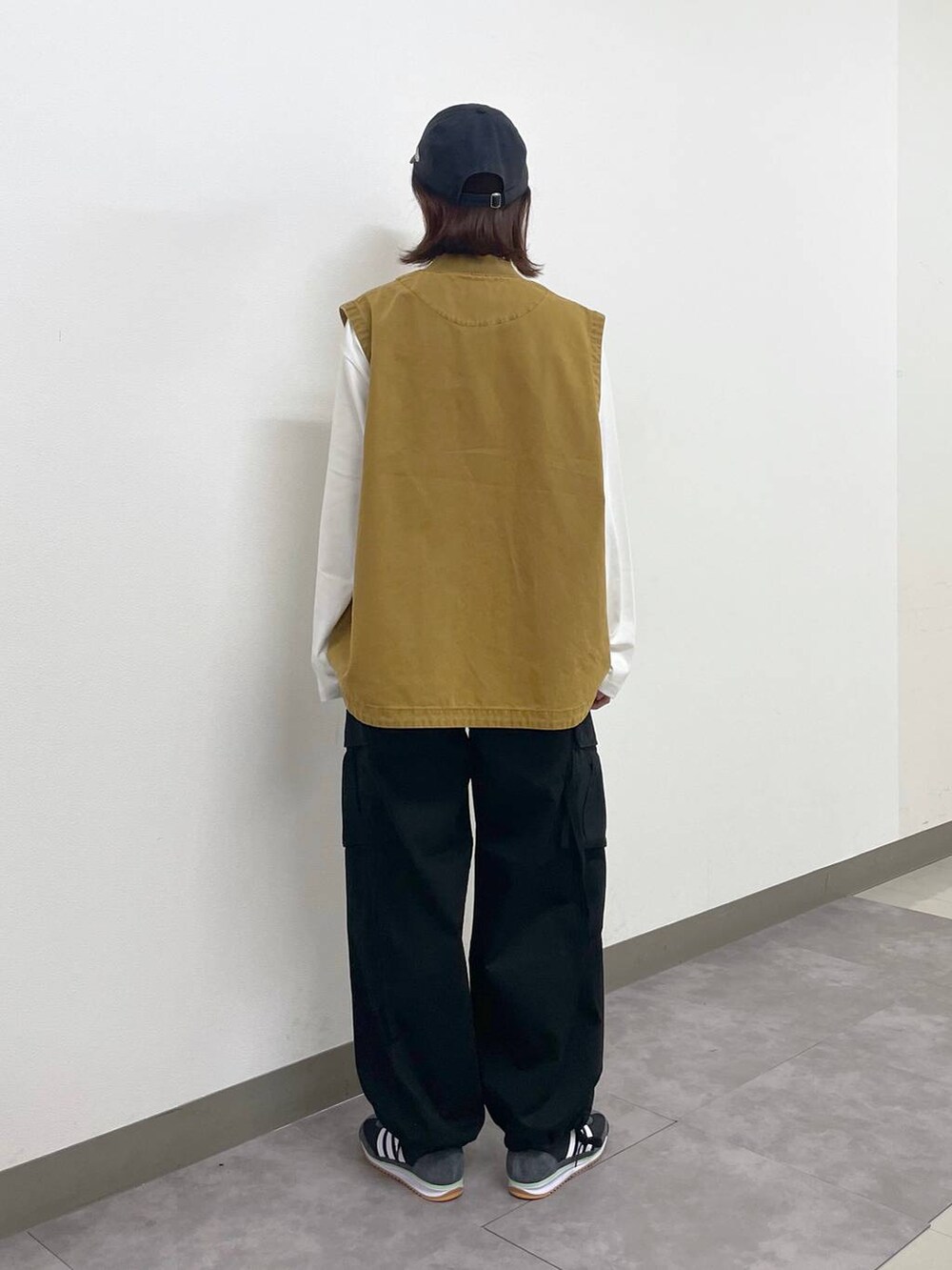 ブラック系のカーゴパンツ、ブラウン系のベスト、ホワイト系のTシャツ/カットソーを着用したレディースの秋コーディネートの4枚目の写真