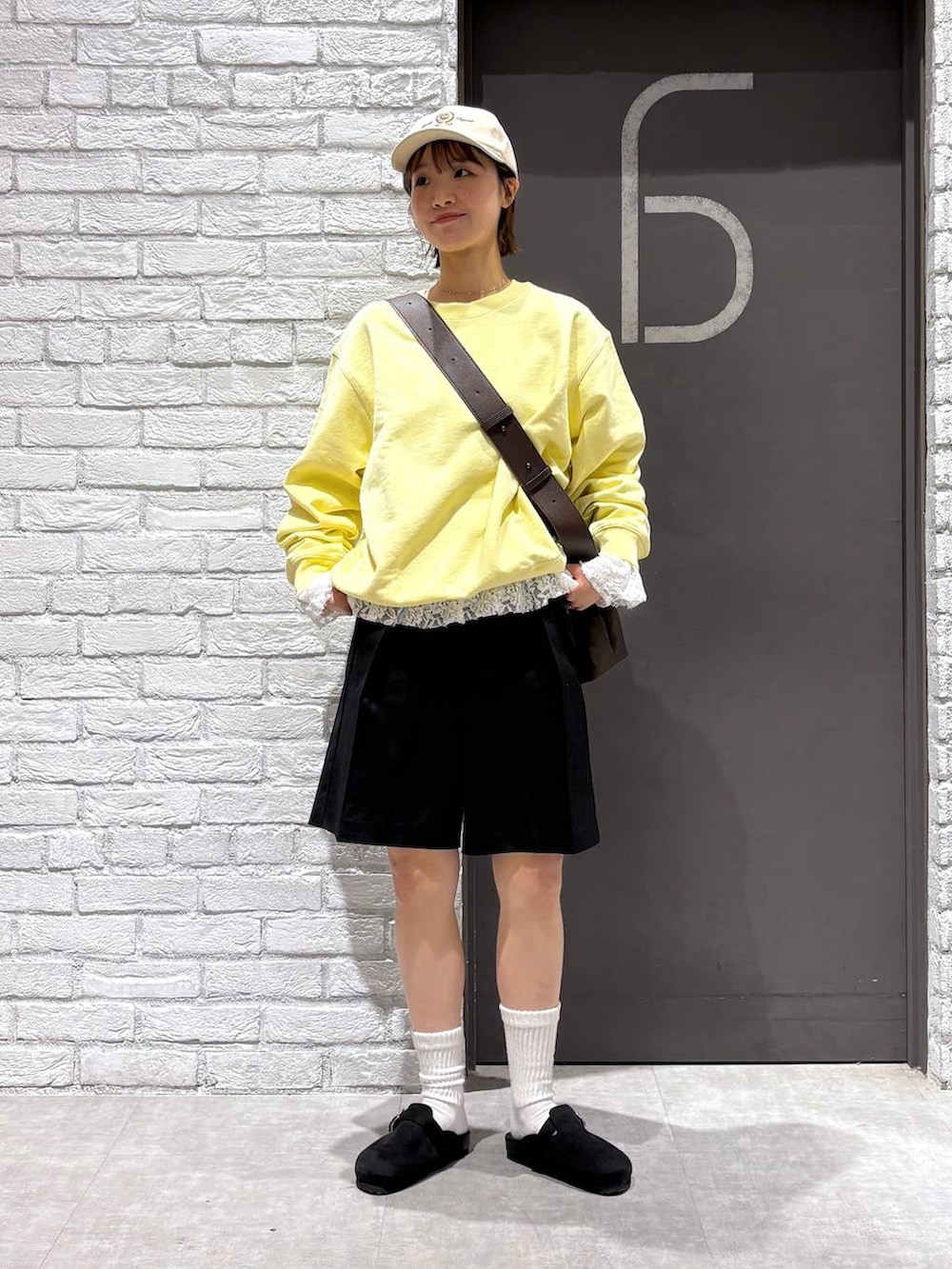 ブラウン系のショルダーバッグ、イエロー系のスウェット、ブラック系のスラックスを着用したレディースの冬コーディネートの6枚目の写真