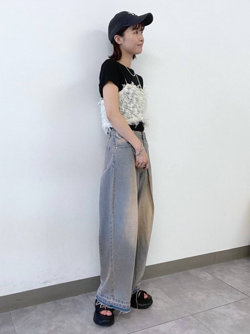 ホワイト系のキャミソール、ブルー系のデニムパンツ、ブラック系のサンダルを着用したレディースの夏コーディネートの2枚目の写真