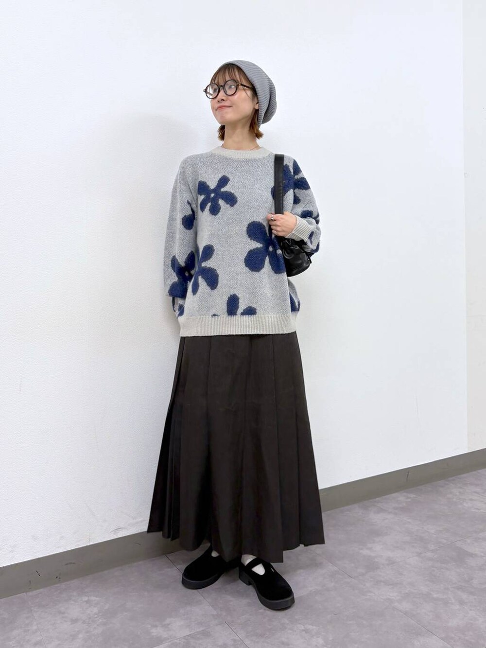 ホワイト系のニット/セーター、ブラウン系のスカート、ブラック系のショルダーバッグを着用したレディースの秋コーディネートの5枚目の写真