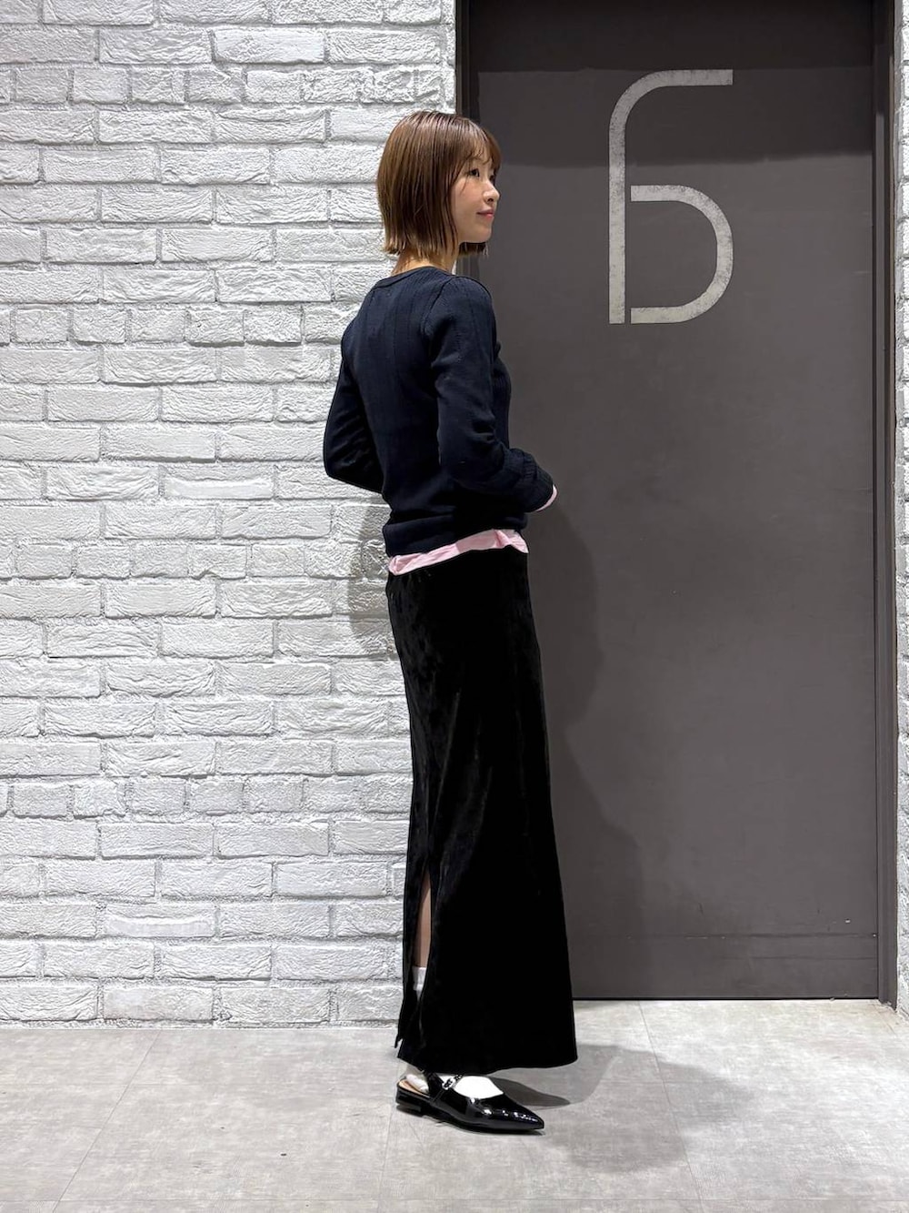 ブラック系のスカート、ブラック系のパンプス、ピンク系のTシャツ/カットソーを着用したレディースの冬コーディネートの5枚目の写真