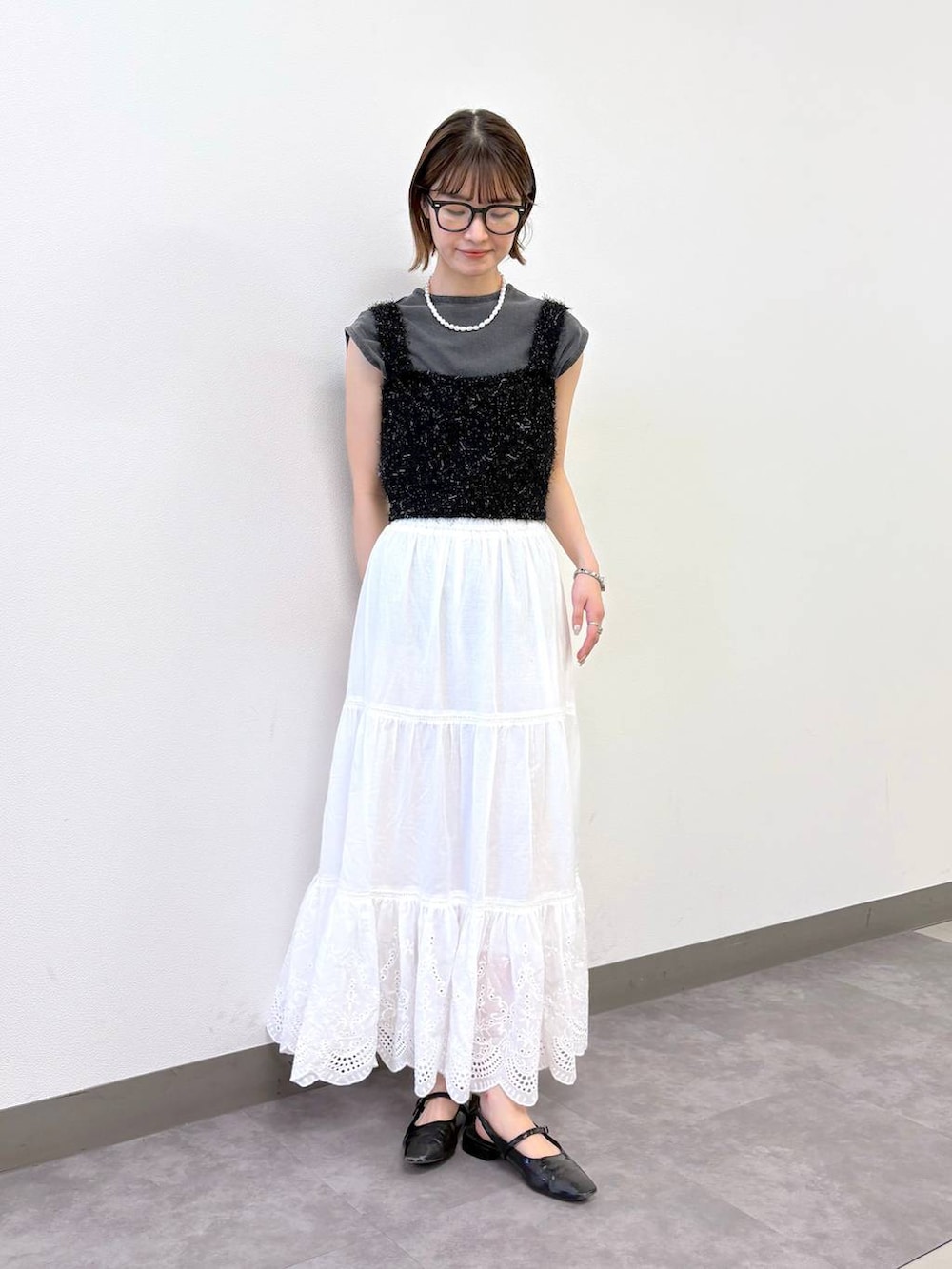 ブラック系のベスト、ブラック系のTシャツ/カットソー、ホワイト系のスカートを着用したレディースの夏コーディネートの4枚目の写真