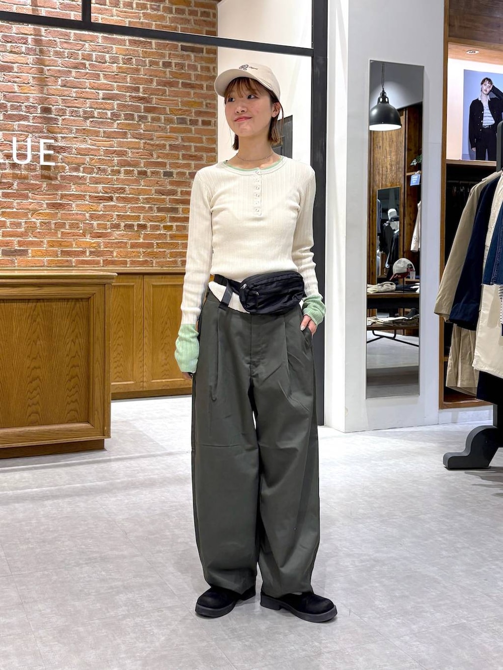 ブラック系のボディバッグ/ウエストポーチ、ホワイト系のニット/セーター、ベージュ系のキャップを着用したレディースの春コーディネートの2枚目の写真