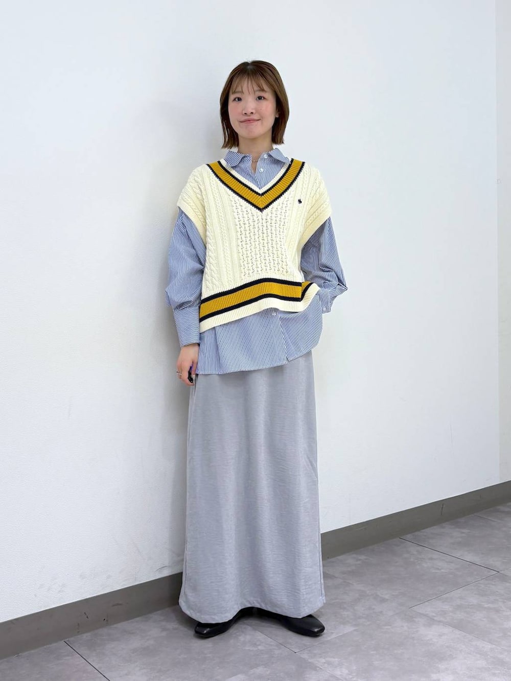 ブラック系のパンプス、ブルー系のシャツ/ブラウス、ホワイト系のベストを着用したレディースの春コーディネートの2枚目の写真