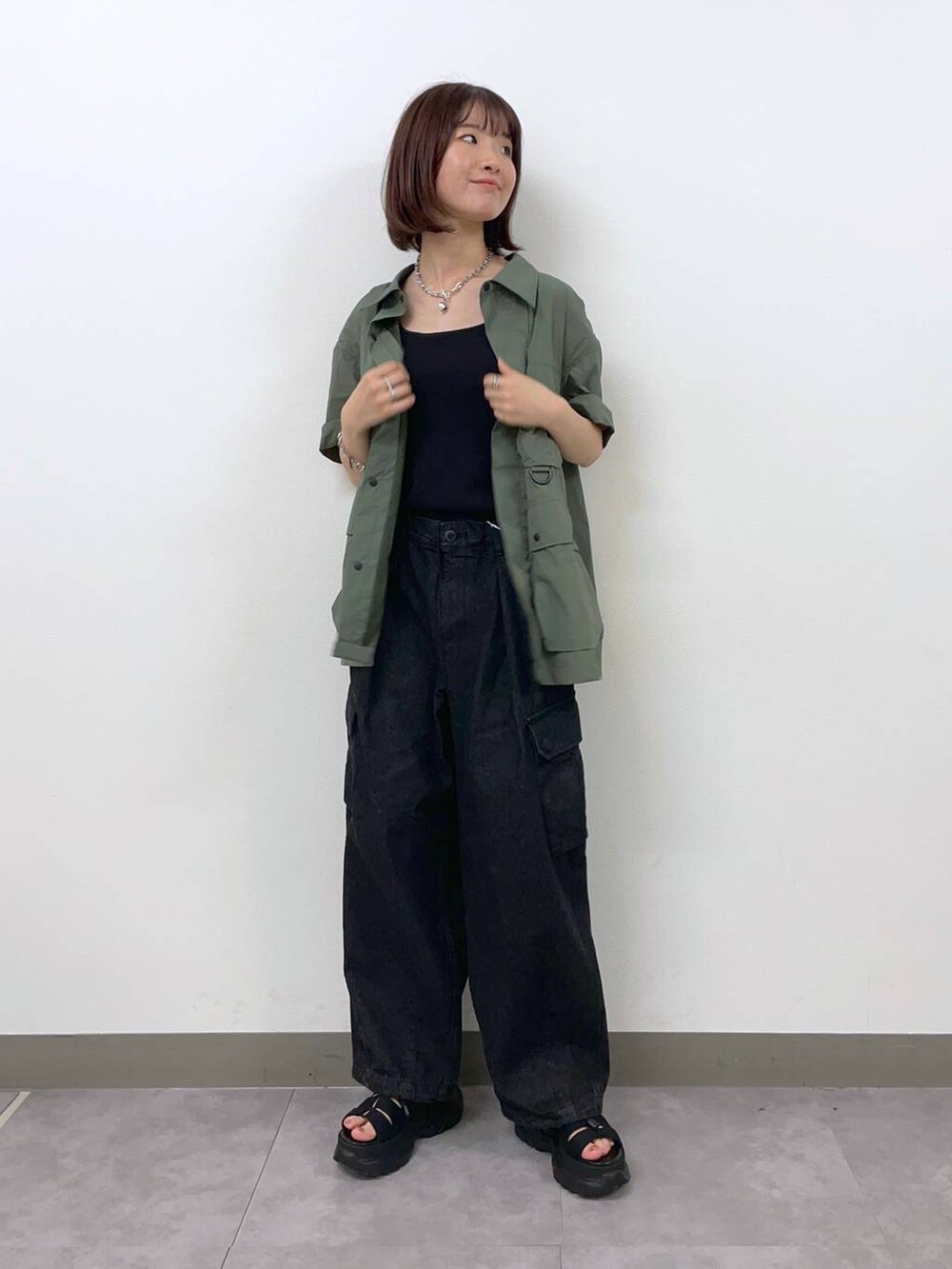 グレー系のデニムパンツ、グリーン系のシャツ/ブラウス、ブラック系のサンダルを着用したレディースの夏コーディネートの2枚目の写真