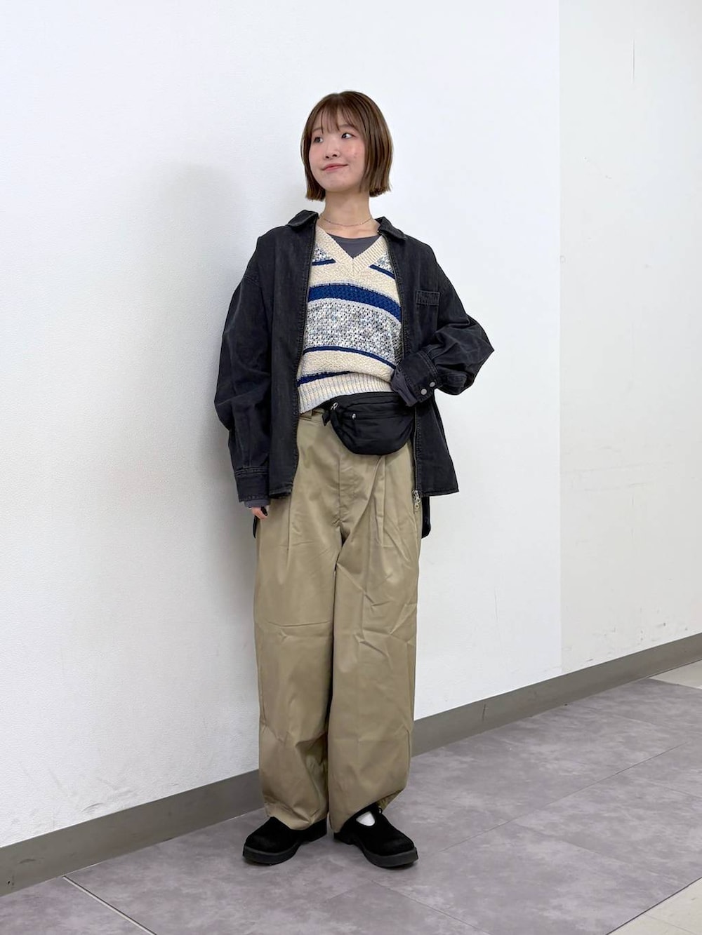 ベージュ系のチノパンツ、ブラック系のボディバッグ/ウエストポーチ、ブルー系のベストを着用したレディースの春コーディネートの2枚目の写真