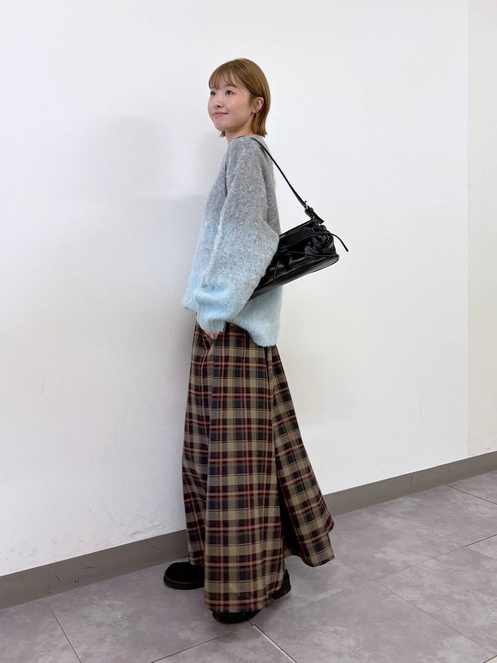 ブラック系のショルダーバッグ、レッド系のスカート、グレー系のニット/セーターを着用したレディースの秋コーディネートの2枚目の写真