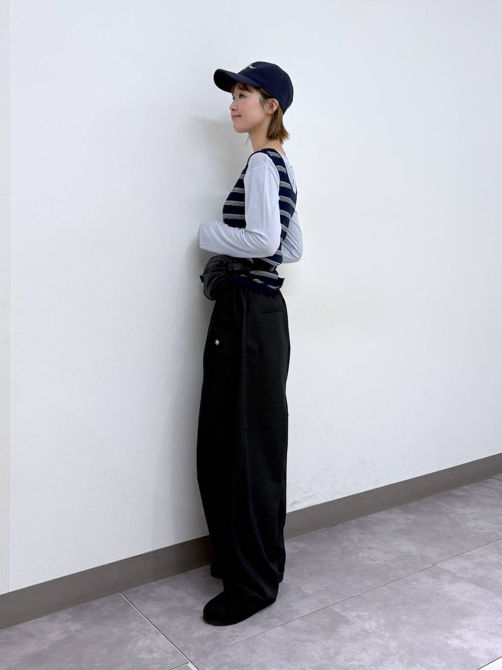 ブラック系のボディバッグ/ウエストポーチ、ブラック系のモカシン/デッキシューズ、ブラック系のスラックスを着用したレディースの春コーディネートの3枚目の写真