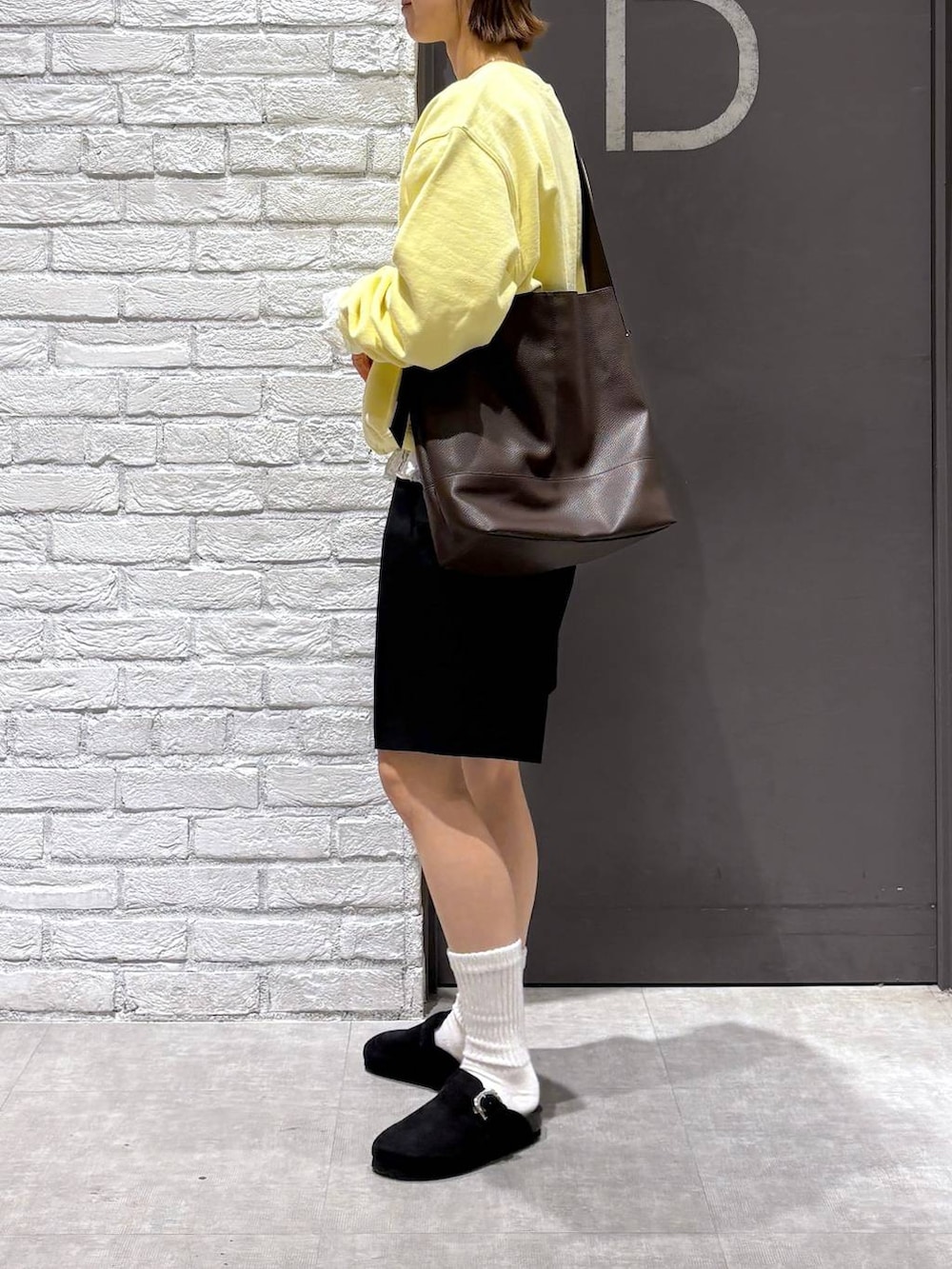 ブラウン系のショルダーバッグ、イエロー系のスウェット、ブラック系のスラックスを着用したレディースの冬コーディネートの3枚目の写真