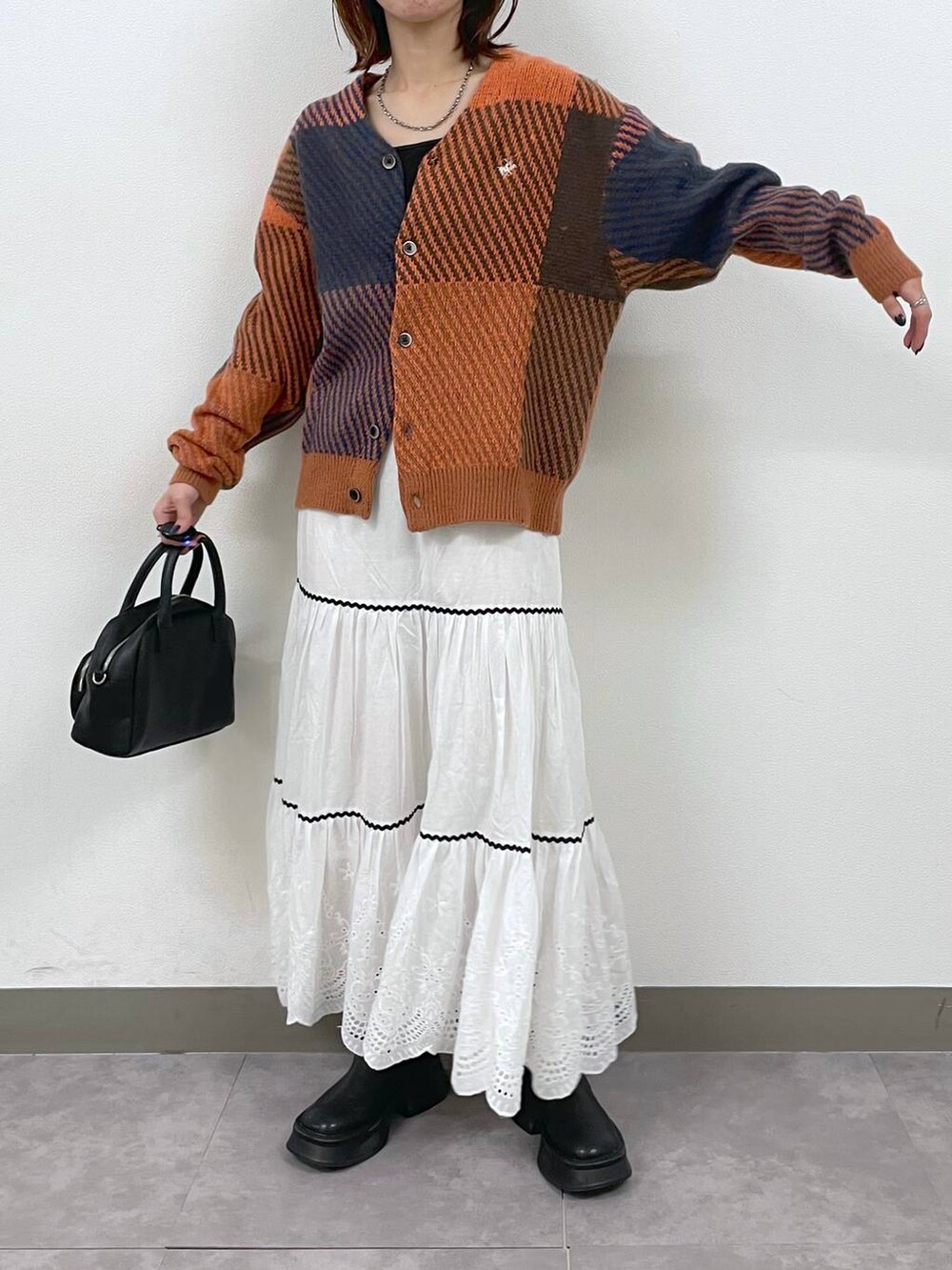 ブラック系のブーツ、ホワイト系のスカート、ブラック系のショルダーバッグを着用したレディースの秋コーディネートの3枚目の写真