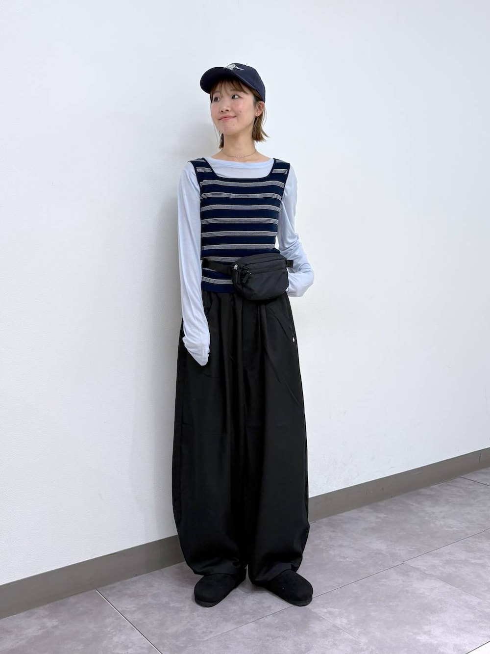 ブラック系のボディバッグ/ウエストポーチ、ブラック系のモカシン/デッキシューズ、ブラック系のスラックスを着用したレディースの春コーディネートの6枚目の写真