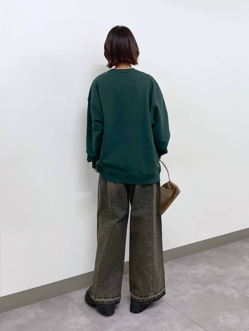 ブラウン系のショルダーバッグ、ブラック系のローファー、グリーン系のスウェットを着用したレディースの冬コーディネートの3枚目の写真