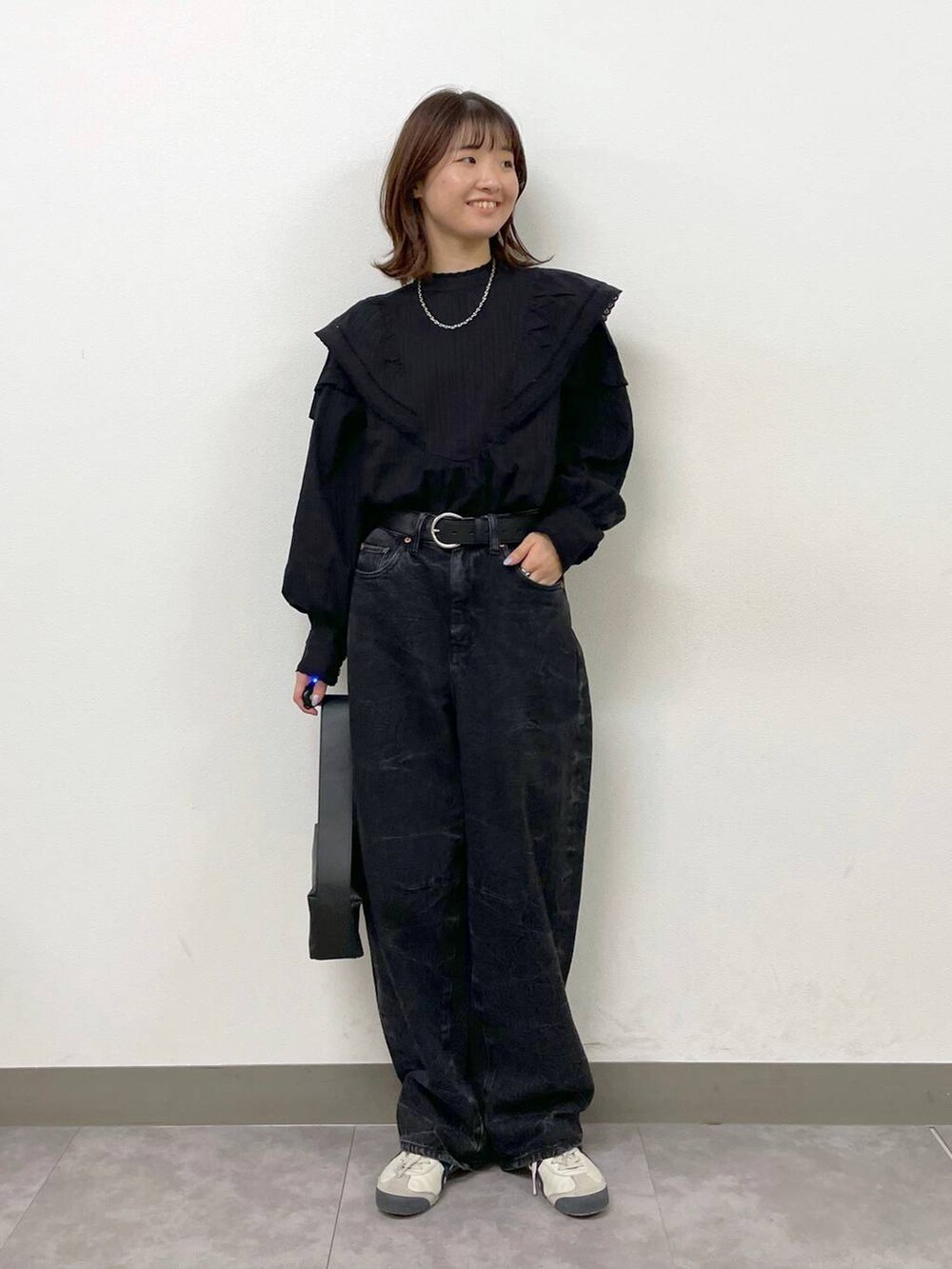 ブラック系のシャツ/ブラウス、ブラック系のショルダーバッグ、ブラック系のデニムパンツを着用したレディースの秋コーディネートの2枚目の写真