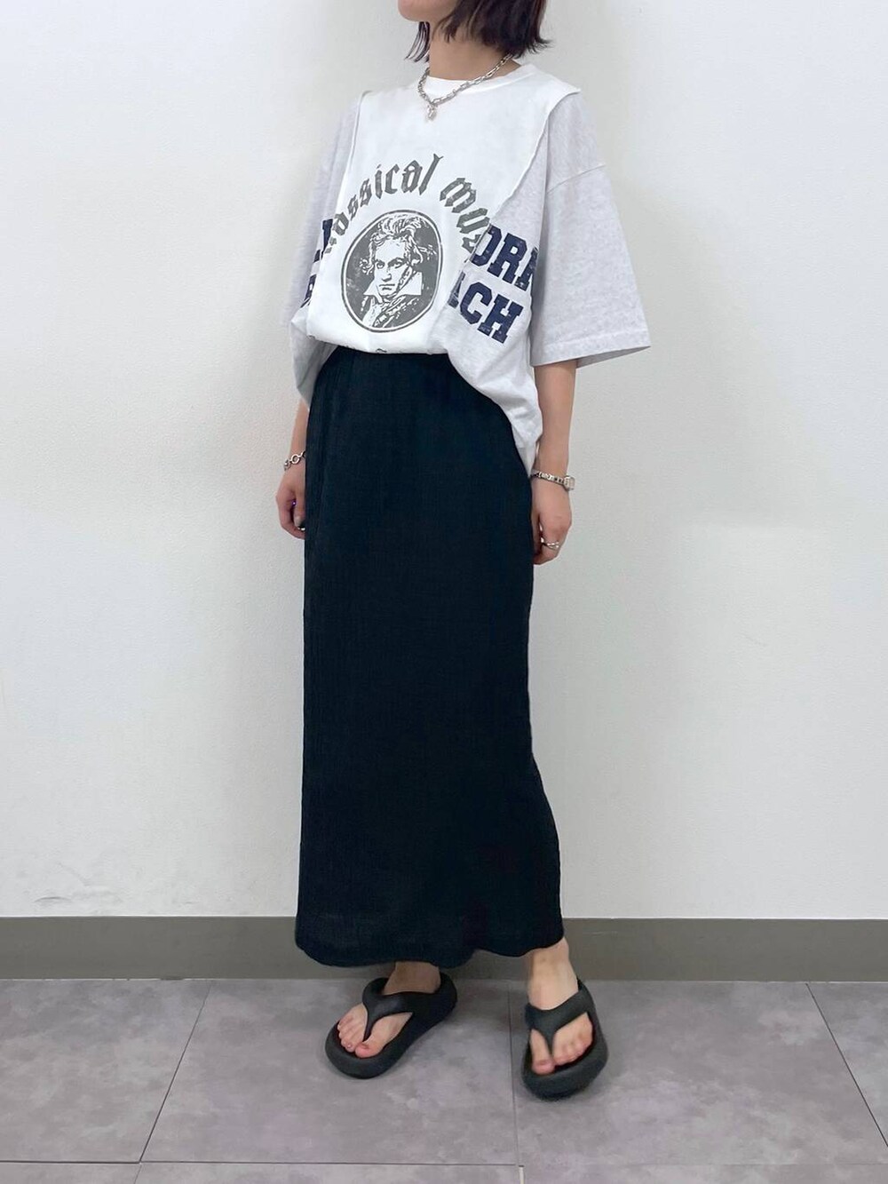 ブラック系のスカート、ホワイト系のTシャツ/カットソー、その他のネックレスを着用したレディースの夏コーディネートの2枚目の写真