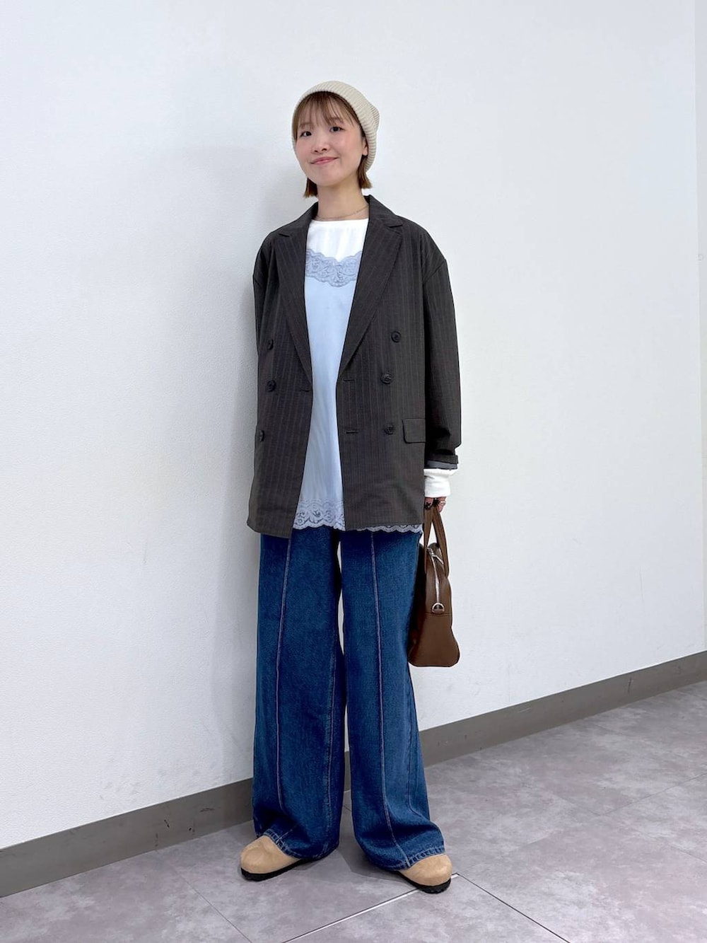 グレー系のテーラードジャケット、ブラウン系のボストンバッグ、ブルー系のデニムパンツを着用したレディースの冬コーディネートの5枚目の写真