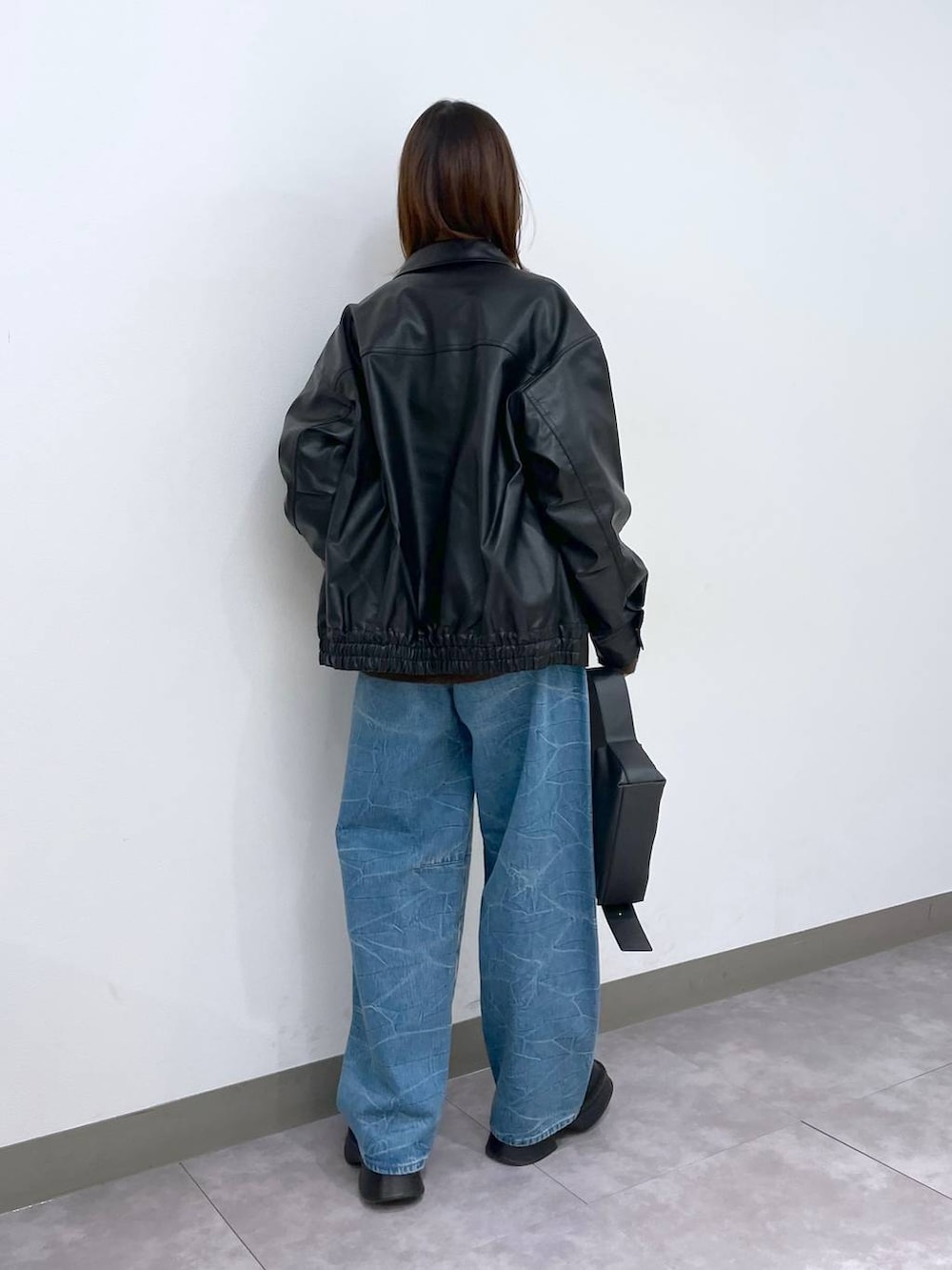 ブラック系のブーツ、ブラック系のショルダーバッグ、ブルー系のデニムパンツを着用したレディースの冬コーディネートの4枚目の写真